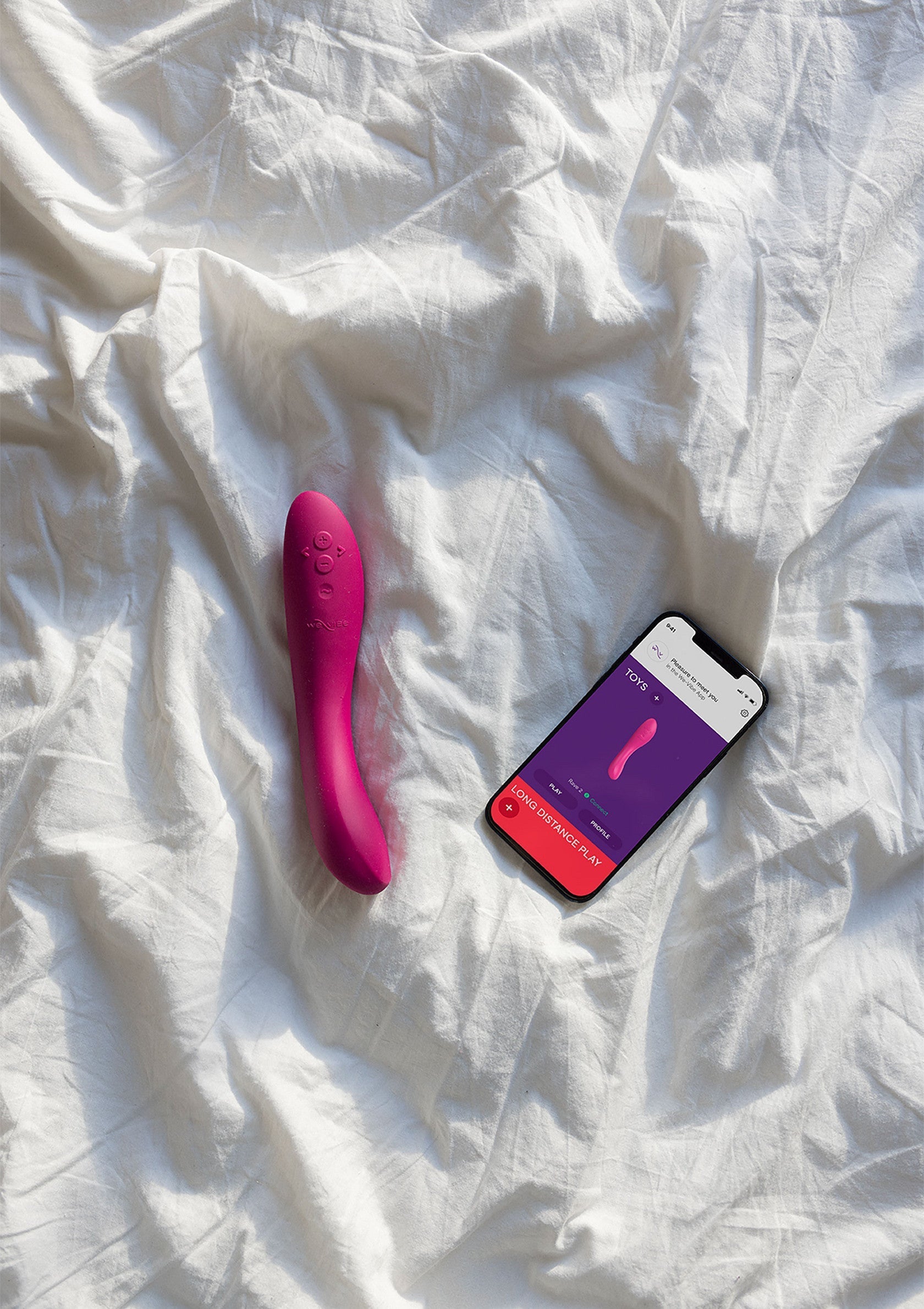 Vibromasseur rose et smartphone sur drap blanc pour le plaisir personnel. Découvrez notre collection!; Roze vibrator en smartphone op wit laken voor persoonlijk plezier. Ontdek onze collectie!; Pink vibrator and smartphone on white sheet for personal pleasure. Discover our collection!
