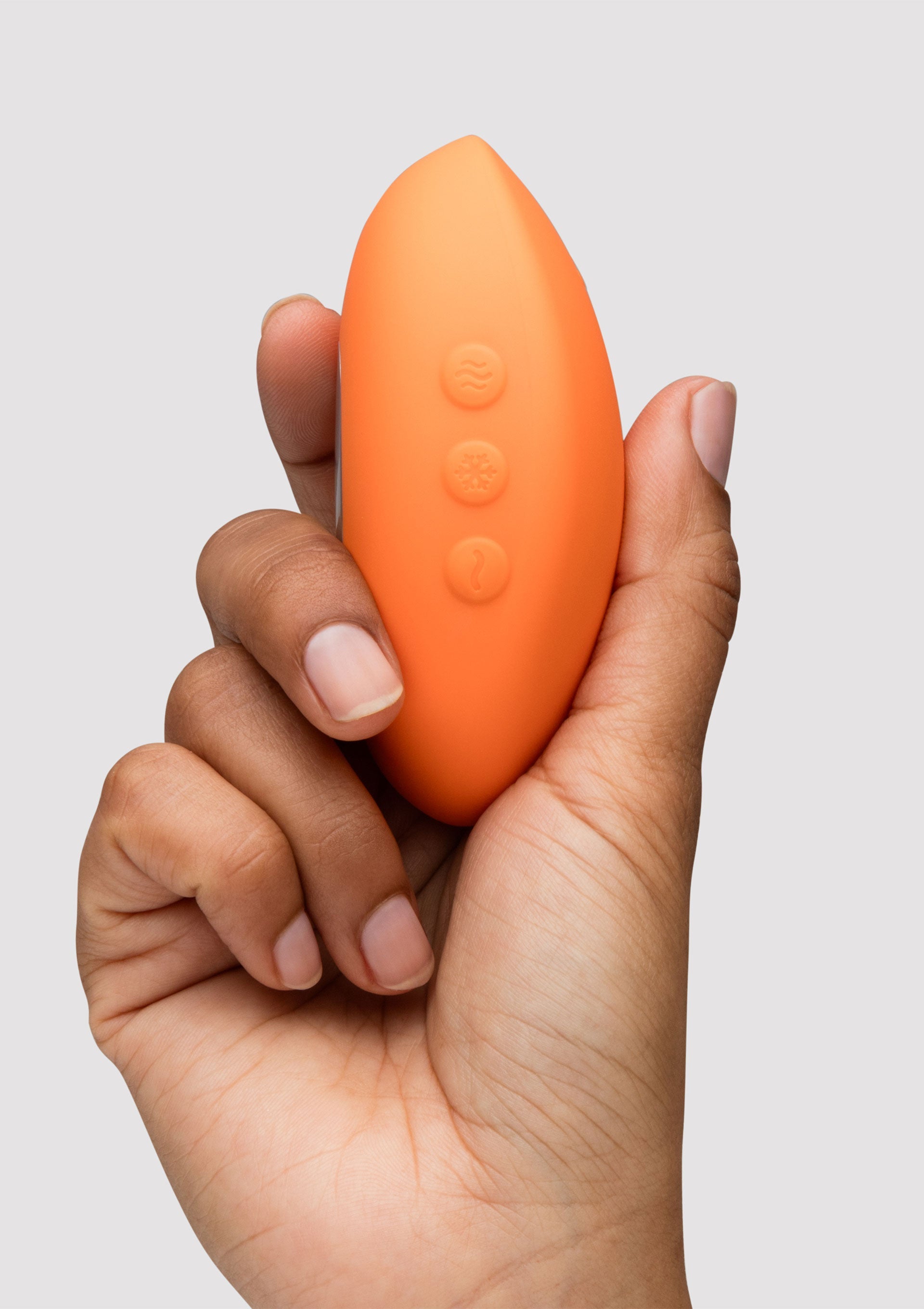 Vibromasseur orange tenu dans une main. Pour le plaisir féminin et l'intimité.; Oranje vibrator in hand. Voor vrouwelijk genot en intimiteit.; Orange vibrator held in hand. For female pleasure and intimacy.