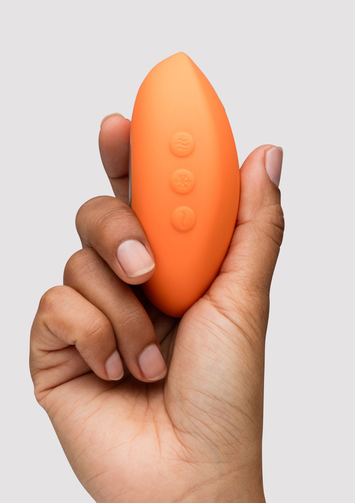 Vibromasseur orange tenu dans une main. Pour le plaisir féminin et l'intimité.; Oranje vibrator in hand. Voor vrouwelijk genot en intimiteit.; Orange vibrator held in hand. For female pleasure and intimacy.