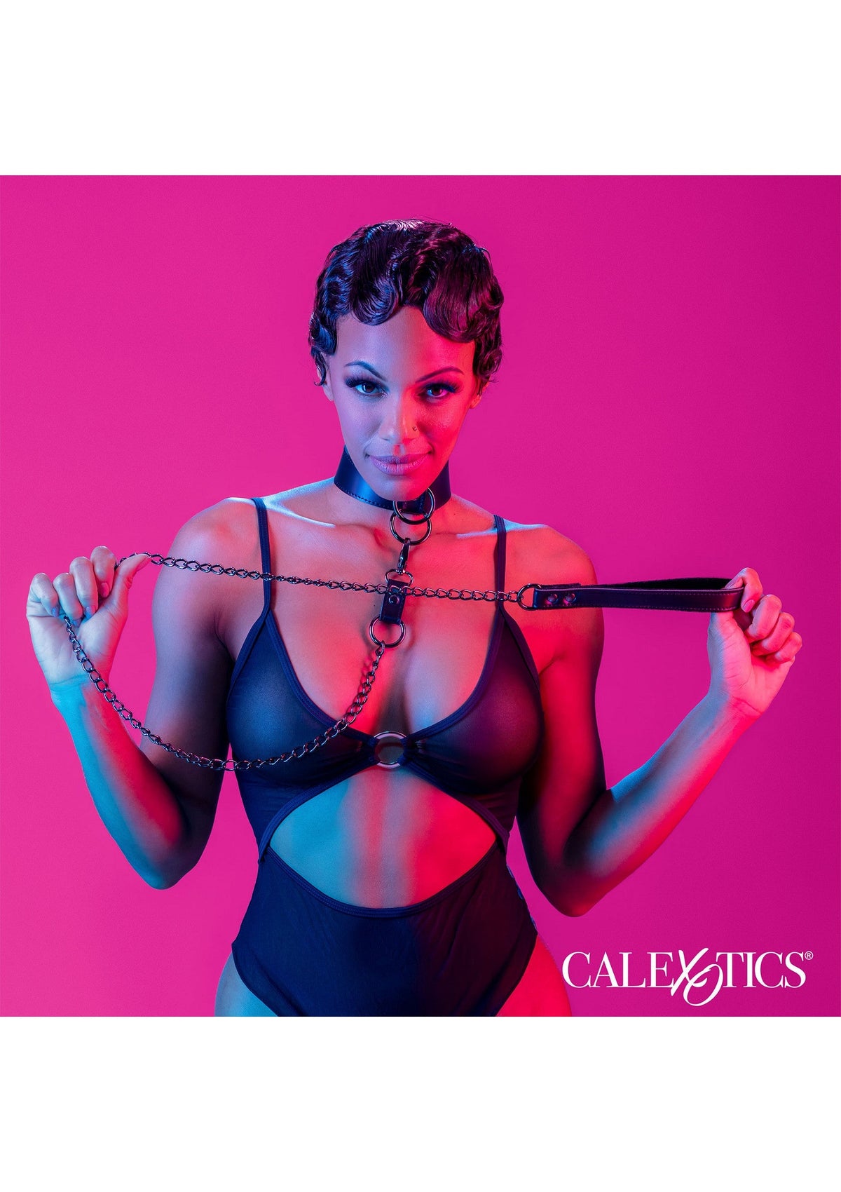 Femme en body noir avec collier et chaîne. Lingerie érotique Calexotics pour une nuit coquine.; Vrouw in zwarte body met halsband en ketting. Calexotics erotische lingerie voor een ondeugende nacht.; Woman in black bodysuit with collar and chain. Calexotics erotic lingerie for a kinky night.