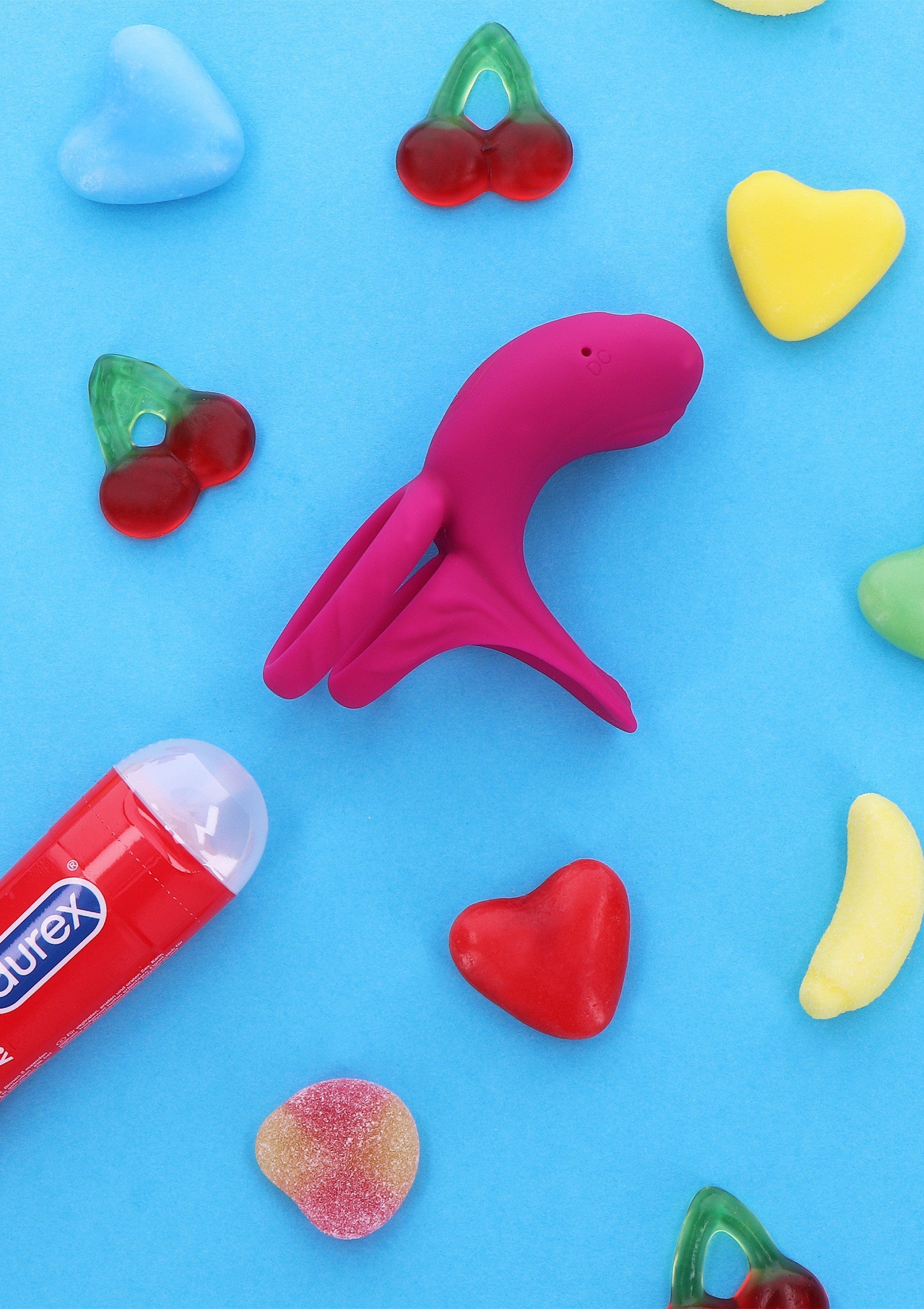 Vibromasseur rose sur fond bleu avec des bonbons, pour pimenter votre vie amoureuse.; Roze vibrator op blauwe achtergrond met snoepjes, om je liefdesleven op te fleuren.; Pink vibrator on blue background with candy, spice up your love life.