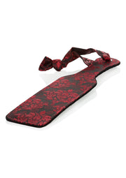 Palette de fessée ornée de motifs floraux rouges et noirs avec un ruban assorti pour une touche de sensualité et de raffinement.; Elegante rood-zwarte paddle met bloemmotief en bijpassend lint, voor een vleugje sensualiteit en verfijning in je spel.; Elegant red and black floral patterned paddle with matching ribbon, for a touch of sensuality and sophistication in your play.