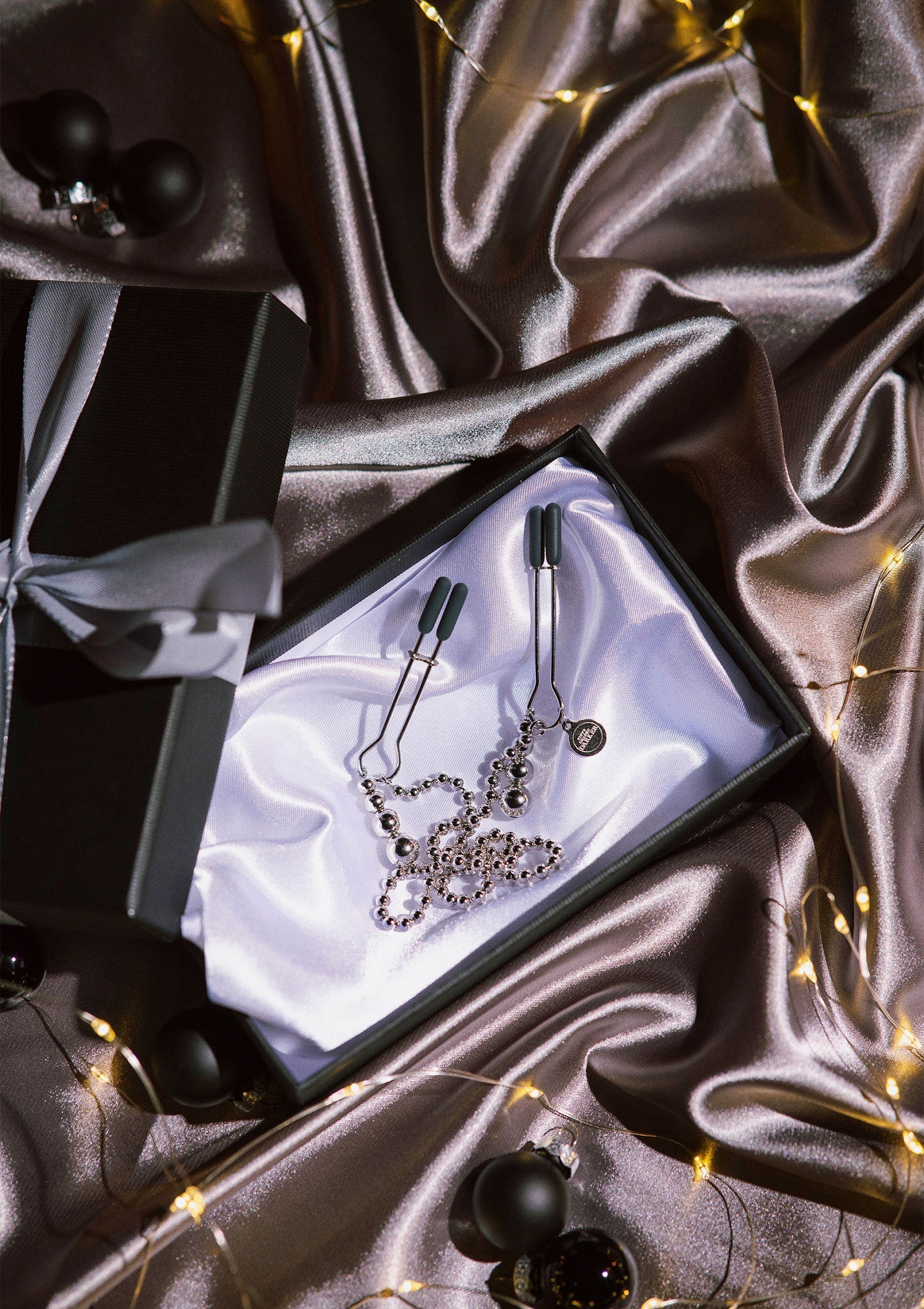 Pince-tétons bijoux en boîte cadeau, ambiance festive et séduisante.; Borstklemmen met juwelen in geschenkdoos, feestelijke en verleidelijke sfeer.; Jeweled nipple clamps in gift box, festive and seductive atmosphere.