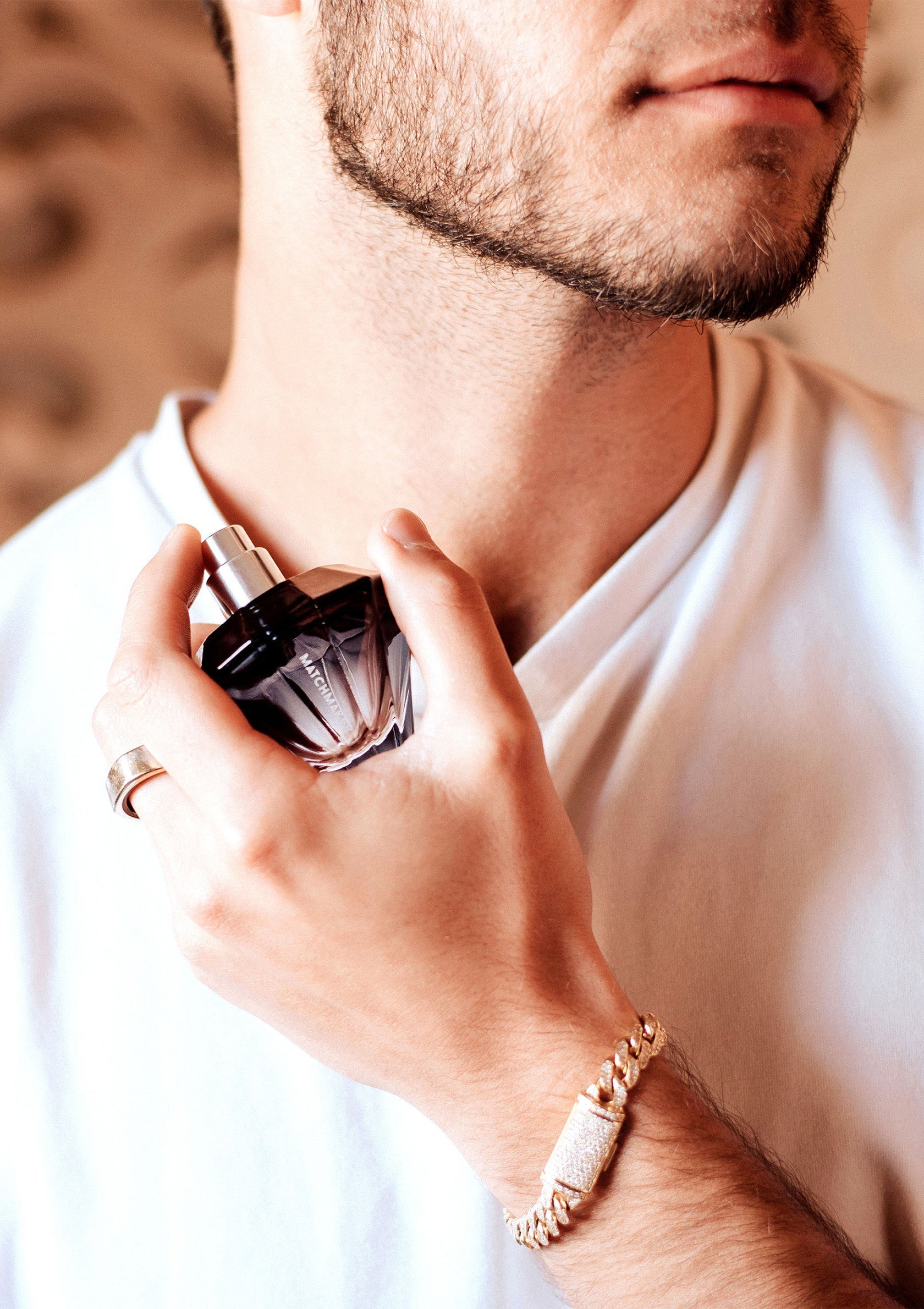 Homme utilisant du parfum. Bracelet et anneau en or.; Man gebruikt parfum. Gouden armband en ring.; Man applying perfume. Gold bracelet and ring.