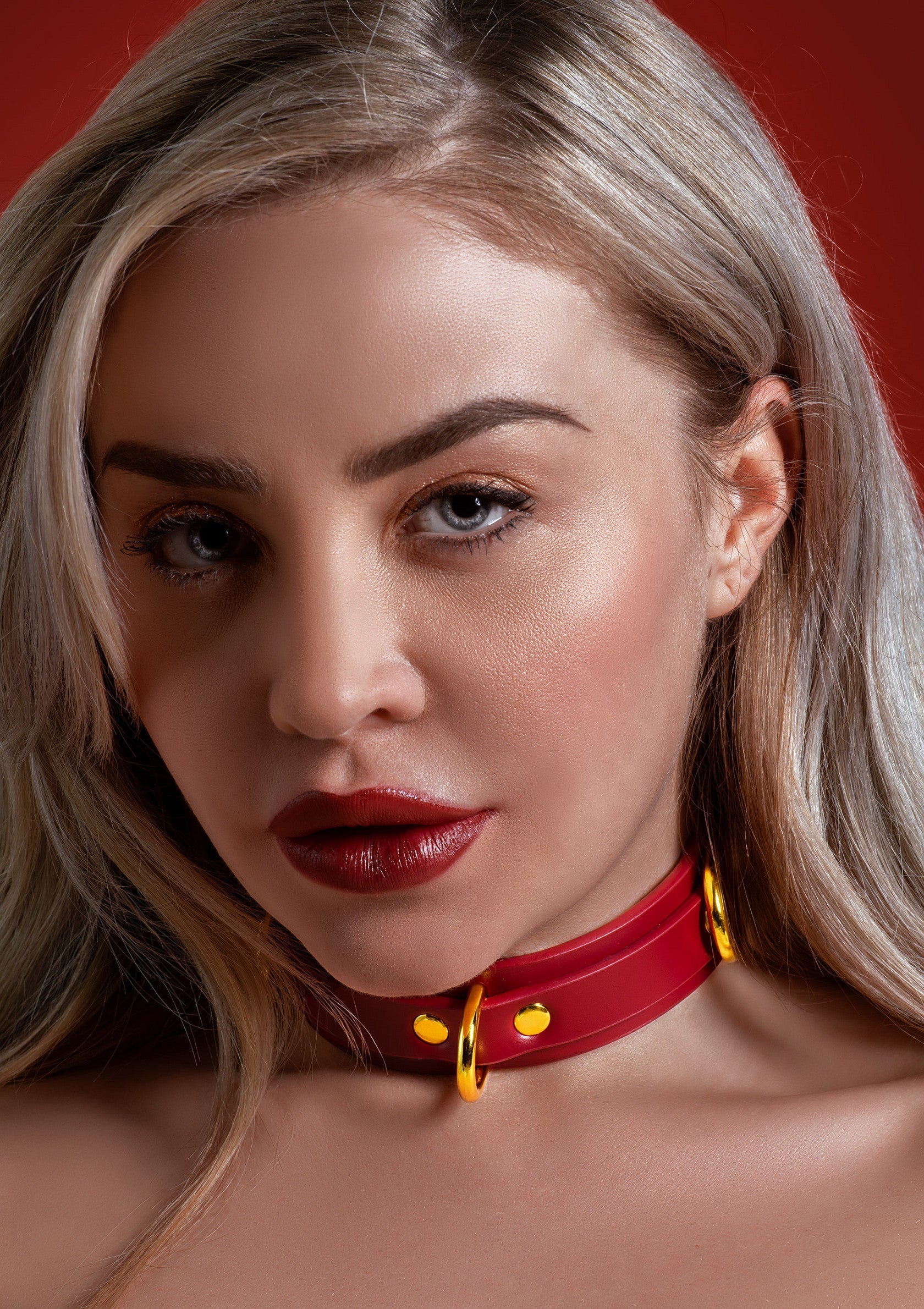 Jolie femme blonde portant un collier rouge élégant. Accessoire mode original et séduisant.; Mooie blonde vrouw met stijlvolle rode halsband. Origineel en verleidelijk modeaccessoire.; Beautiful blonde woman wearing a stylish red collar. Original and seductive fashion accessory.