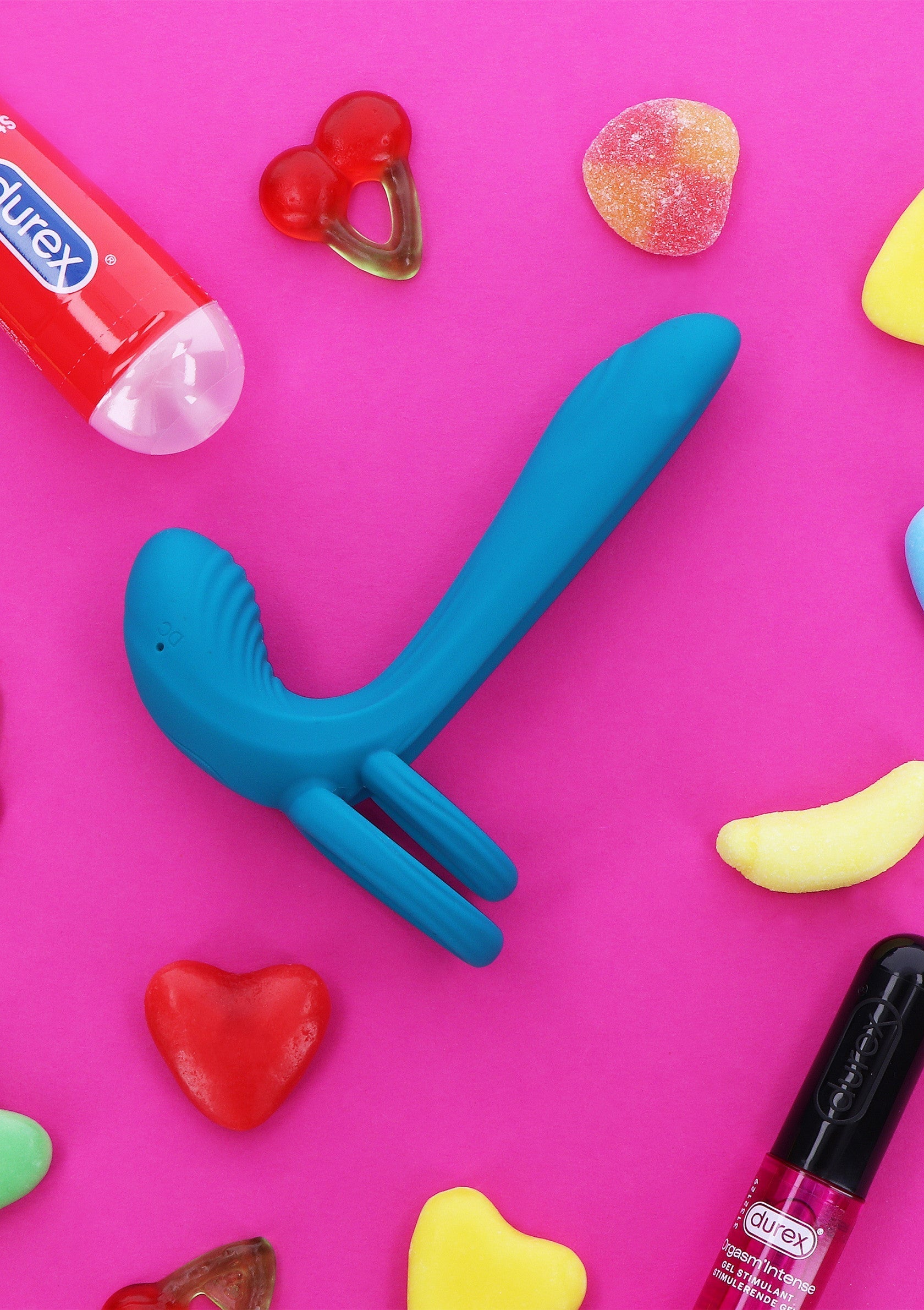 Vibromasseur bleu sur fond rose avec des bonbons. Jouet amusant pour adultes, idéal pour explorer le plaisir seul ou à deux.; Blauwe vibrator op roze achtergrond met snoepjes. Leuk volwassen speeltje, ideaal om alleen of samen plezier te beleven.; Blue vibrator on pink background with candy. Fun adult toy, perfect for exploring pleasure alone or with a partner.