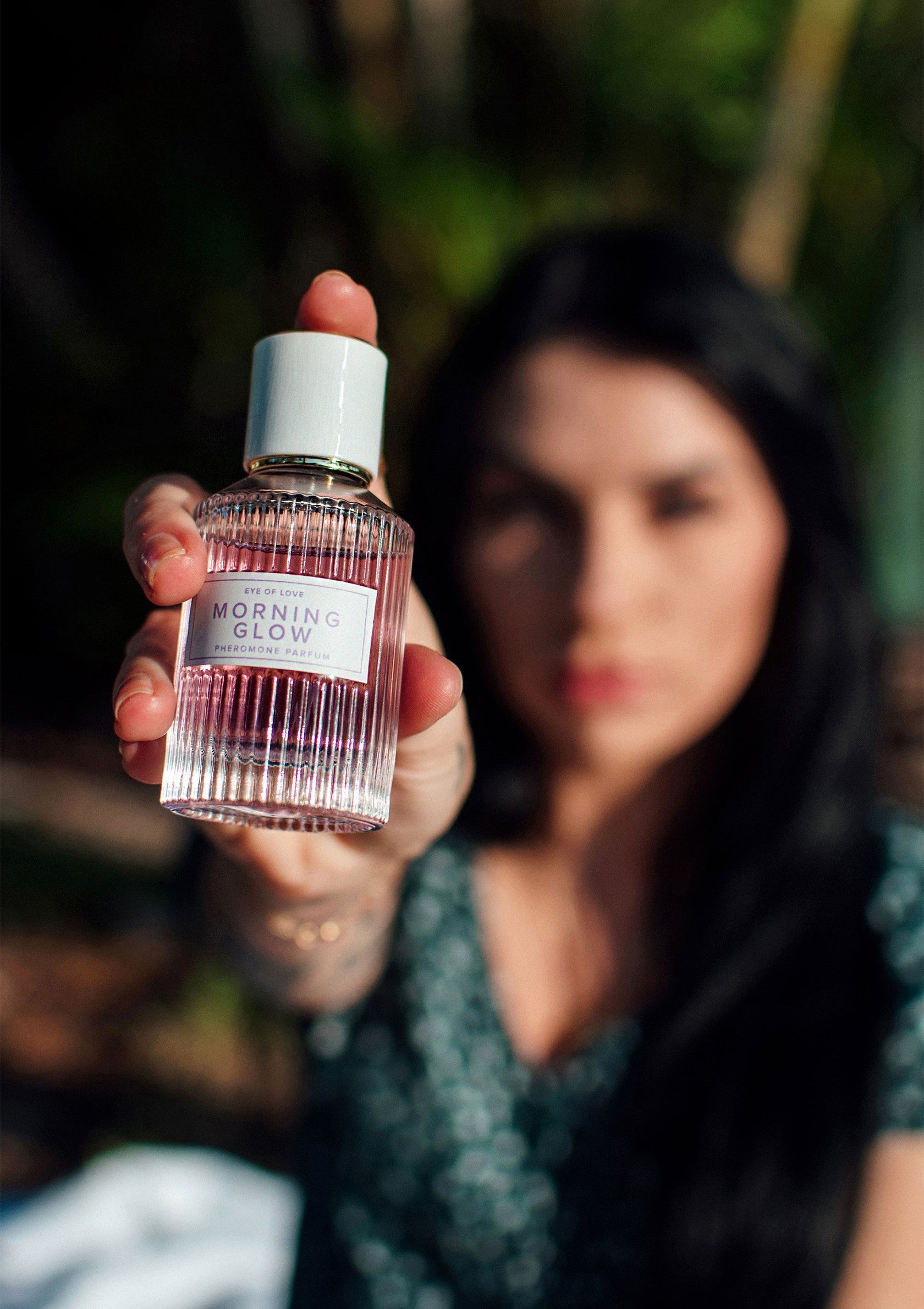 Femme présentant le parfum Morning Glow. Idéal pour un éclat matinal.; Vrouw toont Morning Glow parfum. Ideaal voor een ochtendse gloed.; Woman presenting Morning Glow perfume. Ideal for a morning glow.