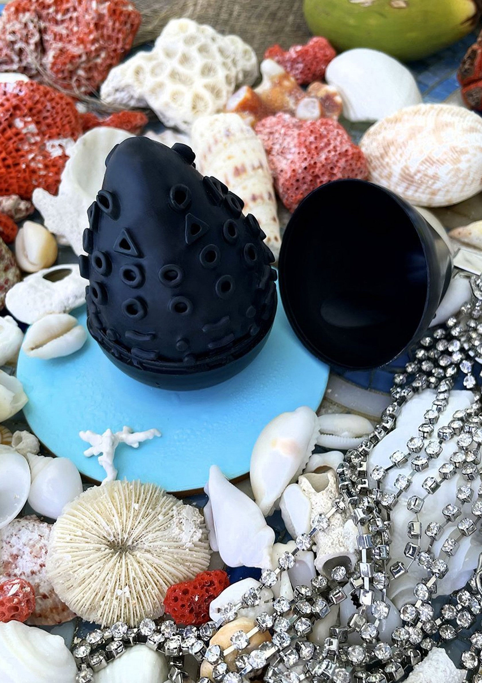 Coquillages, coraux et bijoux scintillants avec un pot noir décoratif. Ambiance marine et élégante.; Schelpen, koralen en sprankelende juwelen met een decoratieve zwarte pot. Maritieme en elegante sfeer.; Seashells, corals, and sparkling jewels with a decorative black pot. Marine and elegant vibes.