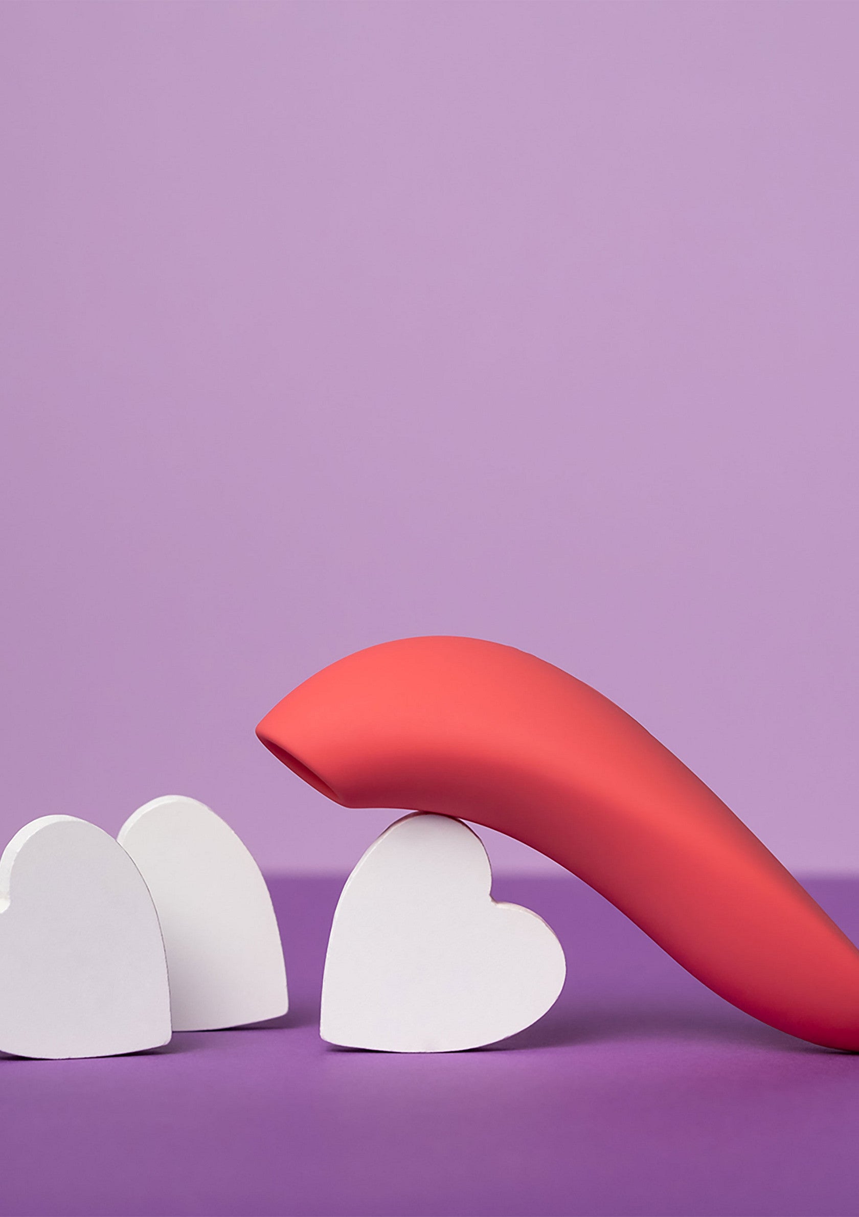 Vibromasseur rose avec des coeurs blancs sur fond violet, pour le plaisir et la romance.; Roze vibrator met witte harten op paarse achtergrond, voor plezier en romantiek.; Pink vibrator with white hearts on purple background, for pleasure and romance.