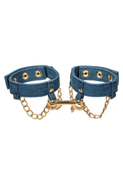 Menottes en jean avec chaîne dorée pour un look audacieux et original.; Denim handboeien met gouden ketting voor een gewaagde en unieke look.; Denim handcuffs with gold chain for a bold and unique look.