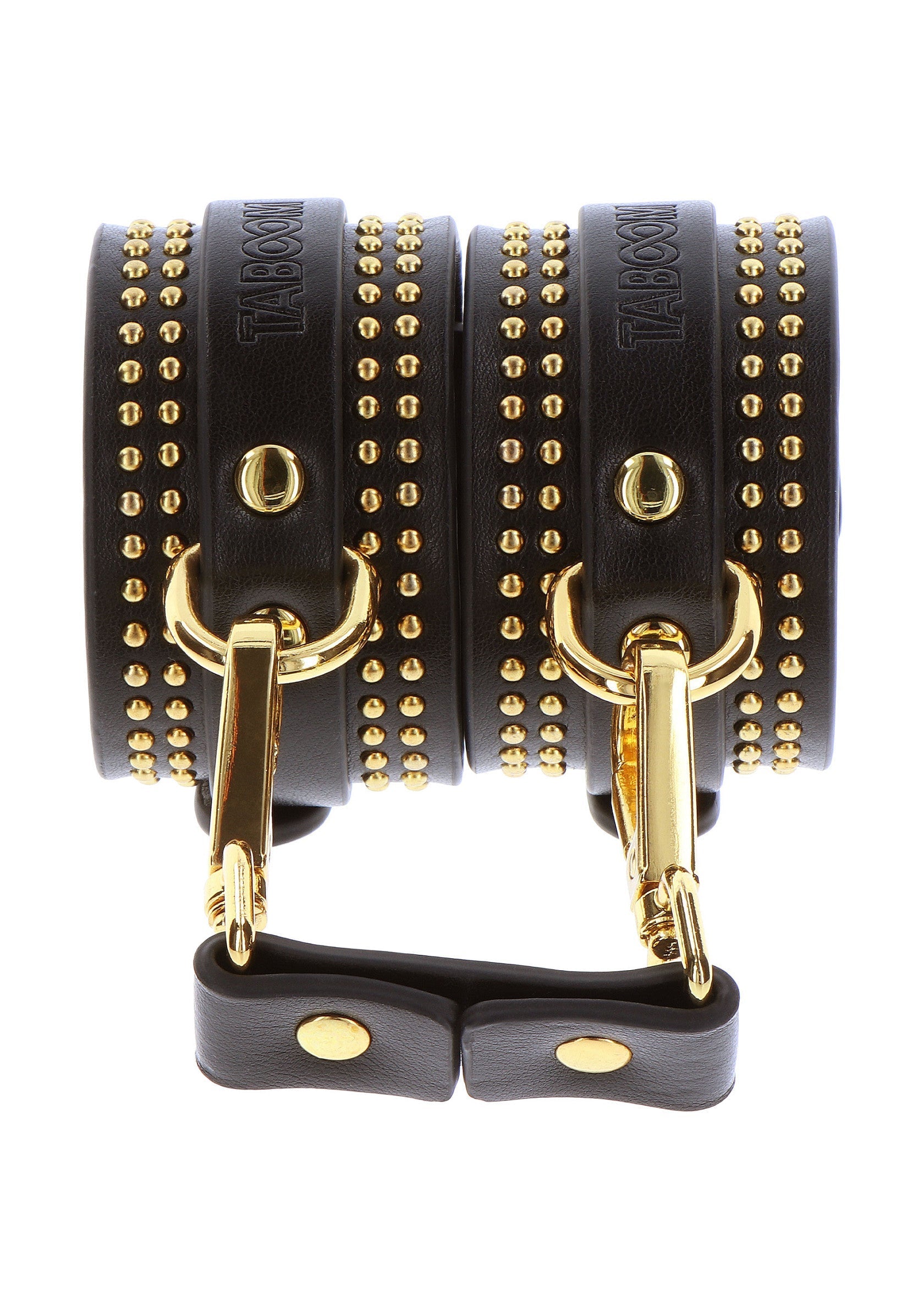 Menottes en cuir noir cloutées or de Taboom. Accessoires de jeu de rôle pour adultes.; Zwarte lederen handboeien met gouden studs van Taboom. Accessoires voor volwassen rollenspellen.; Black leather handcuffs with gold studs by Taboom. Adult role play accessories.