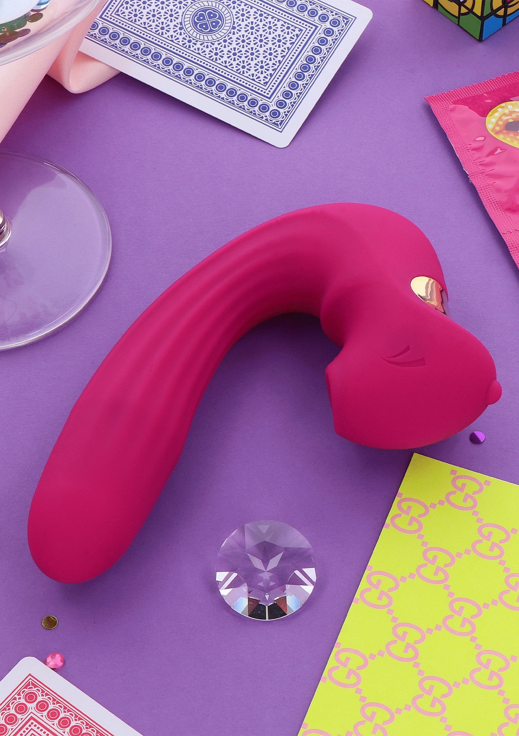 Vibromasseur rose sur fond violet avec accessoires coquins pour adultes.; Roze vibrator op paarse achtergrond met ondeugende accessoires voor volwassenen.; Pink vibrator on purple background with playful adult accessories.