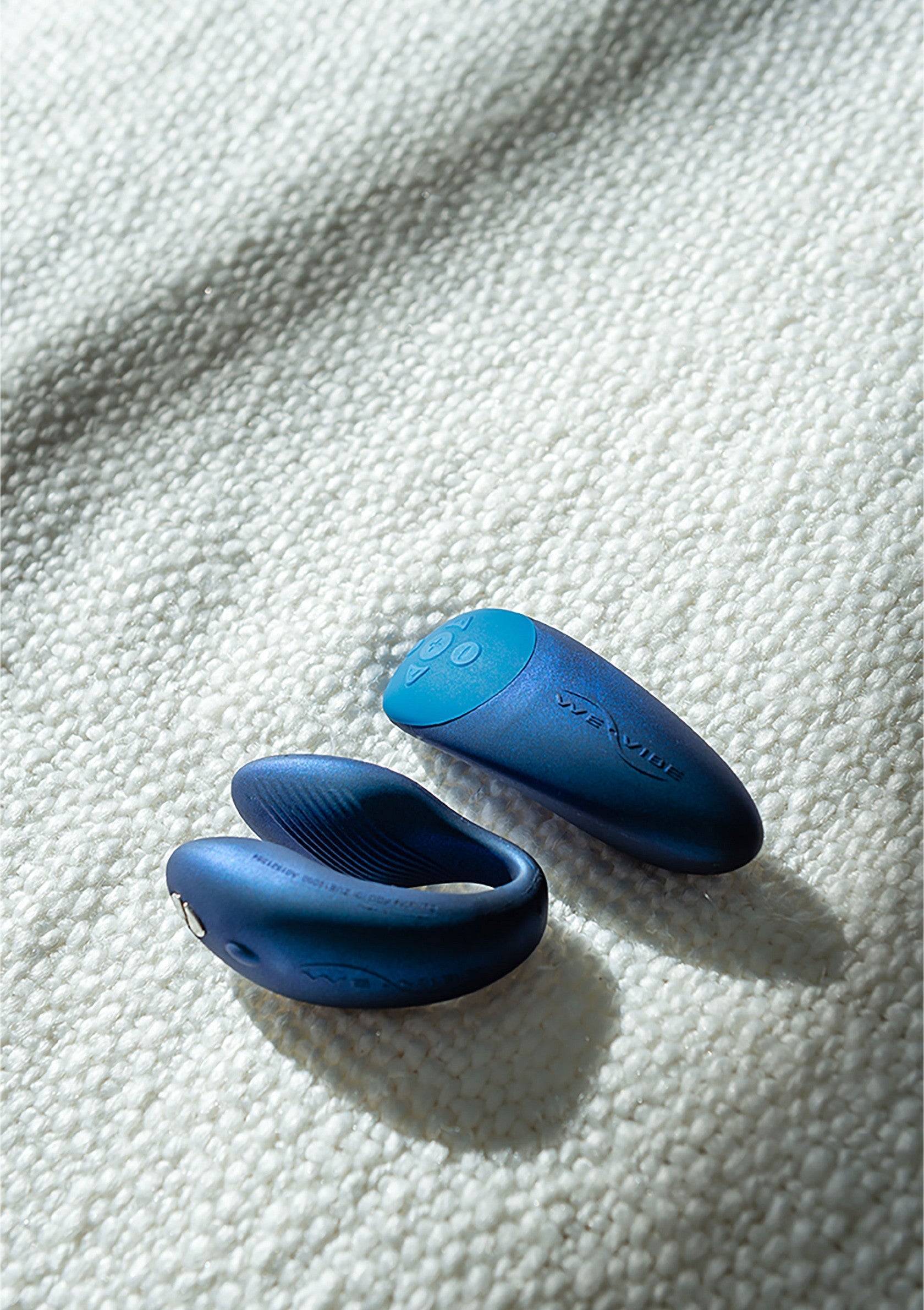 Couple jouets sexuels We-Vibe bleus pour le plaisir intime, sur une couverture texturée.; Blauwe We-Vibe seksspeeltjes voor intiem plezier, op een gestructureerde deken.; Blue We-Vibe sex toys for intimate pleasure, on a textured blanket.
