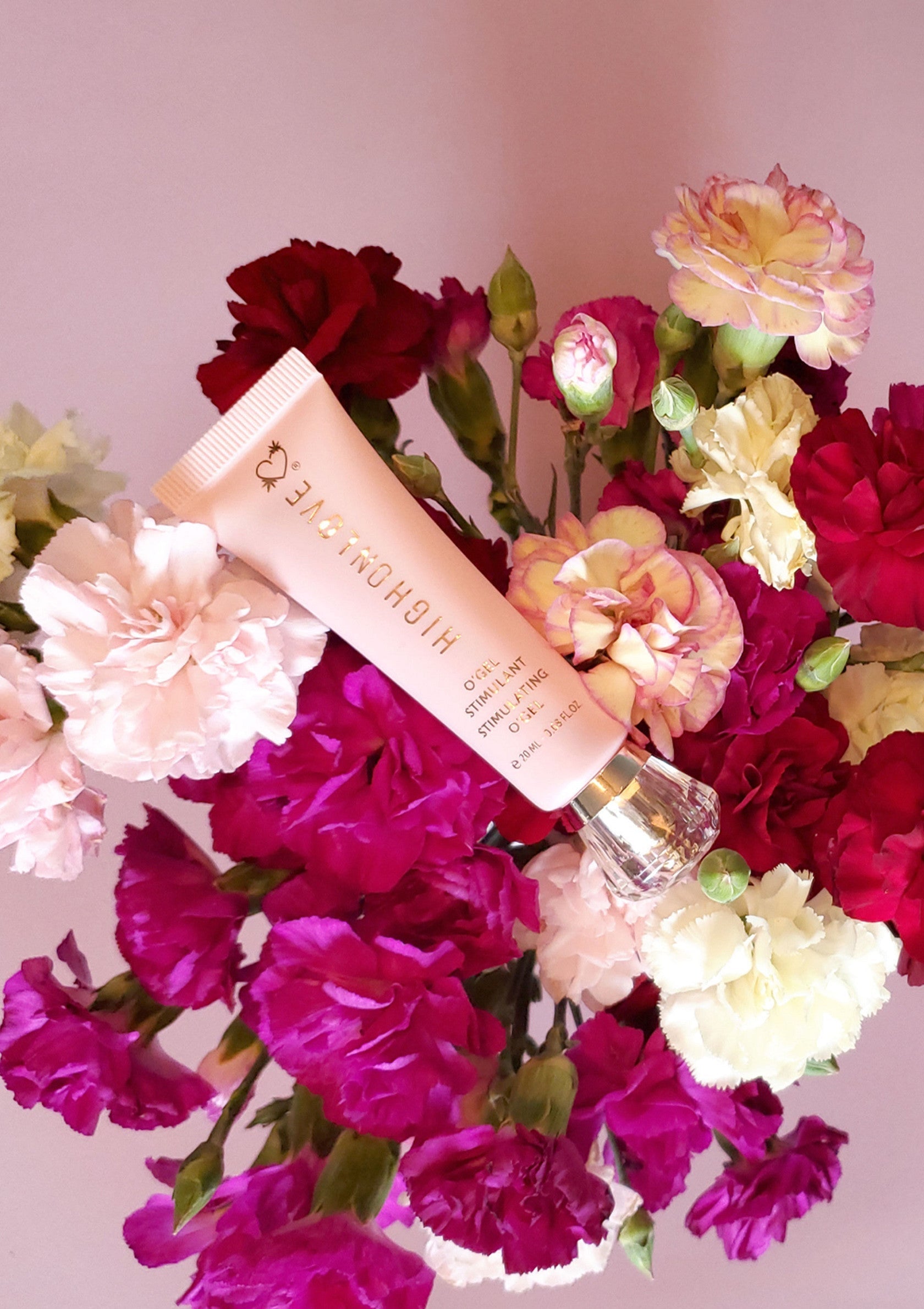 Crème HIGH ON LOVE stimulante, présentée sur un bouquet de fleurs colorées. Produits de beauté et bien-être.; HIGH ON LOVE stimulerende crème, gepresenteerd op een boeket kleurrijke bloemen. Schoonheid en wellness producten.; HIGH ON LOVE stimulating cream, presented on a bouquet of colorful flowers. Beauty and wellness products.