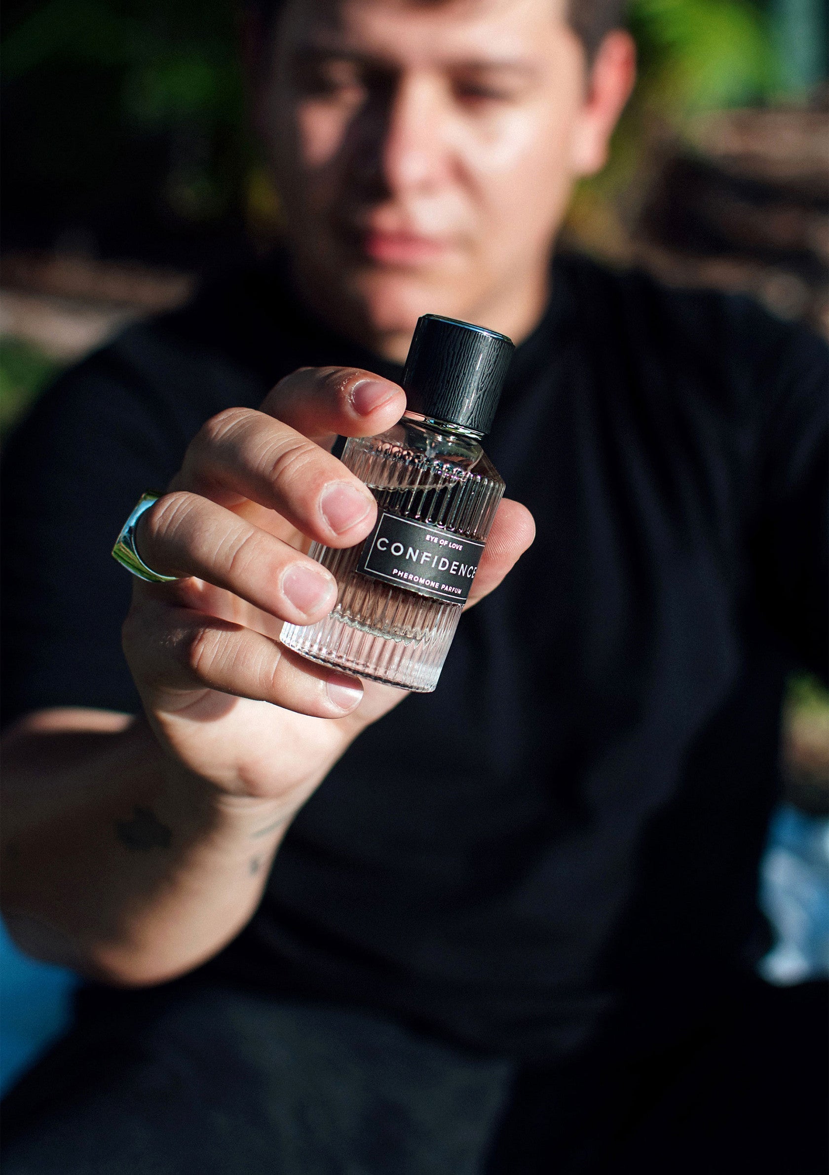 Homme présentant un flacon de parfum "Confidence". Découvrez ce parfum unique pour homme.; Man toont "Confidence" parfumflesje. Ontdek deze unieke herengeur.; Man presents "Confidence" perfume bottle. Discover this unique men's fragrance.