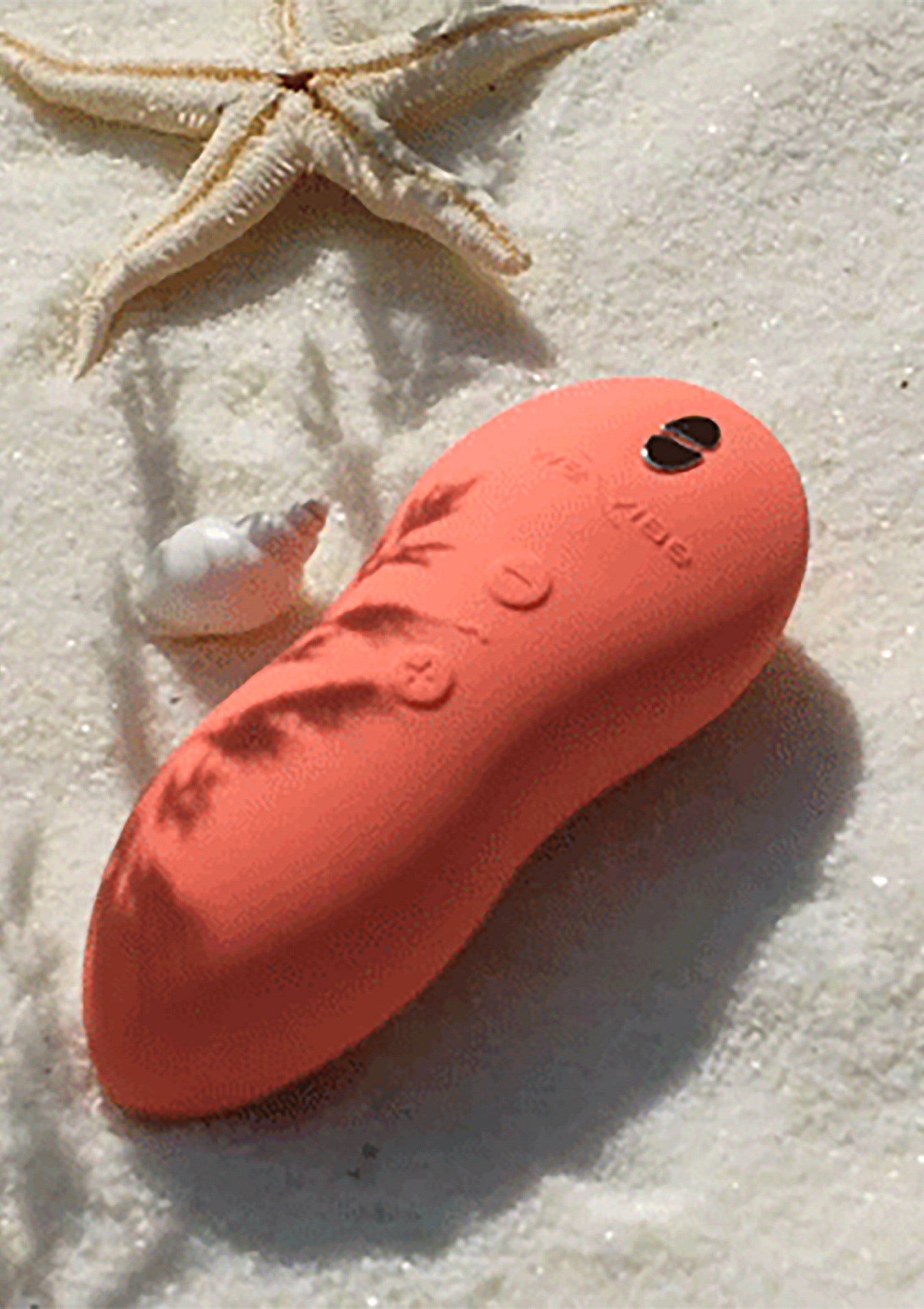 Vibreur orange sur le sable avec étoile de mer. Parfait pour des moments de plaisir et de détente.; Oranje vibrator op het zand met zeester. Perfect voor plezier en ontspanning.; Orange vibrator on sand with a starfish. Perfect for pleasure and relaxation.