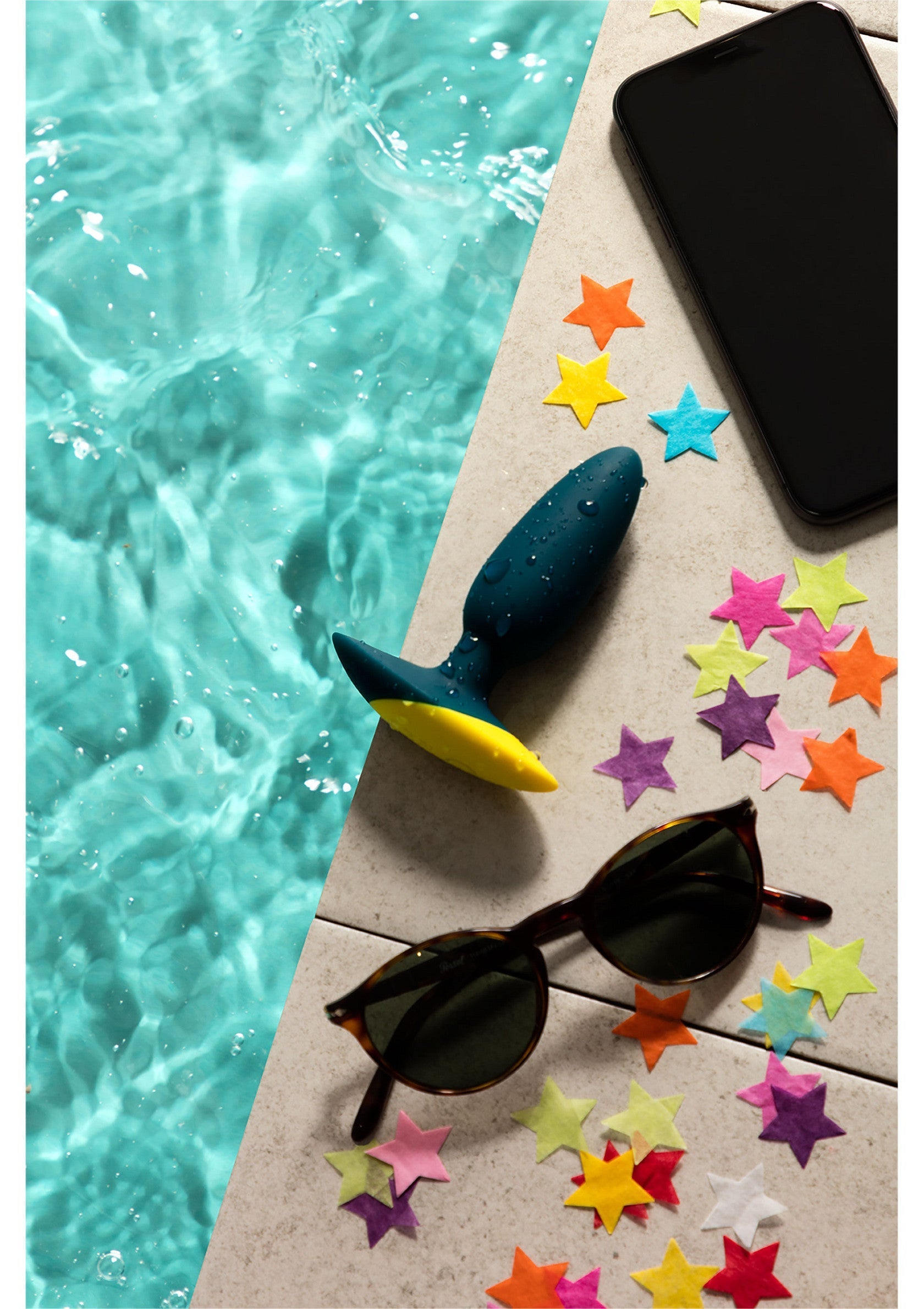 Vibromasseur bleu et jaune à côté d'une piscine avec lunettes de soleil et téléphone. Parfait pour l'été! ; Blauwe en gele vibrator naast zwembad met zonnebril en telefoon. Perfect voor de zomer! ; Blue and yellow vibrator next to pool with sunglasses and phone. Perfect for summer! 
