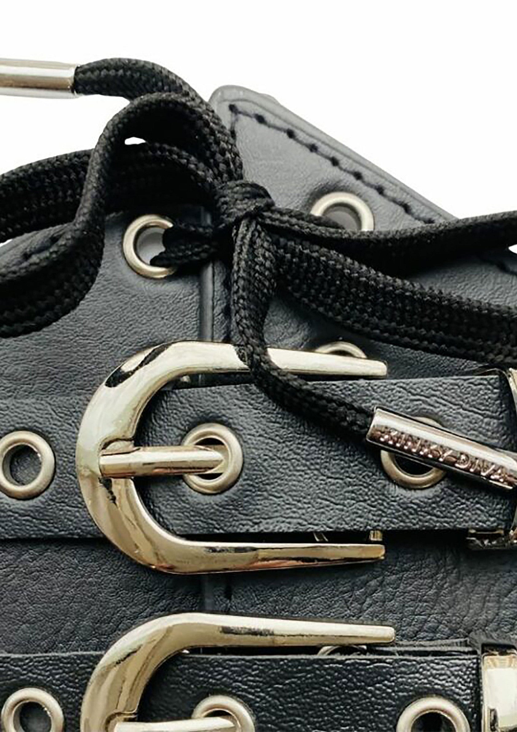 Détail de chaussure noire avec lacets et boucles argentées, style audacieux et tendance.; Detail van zwarte schoen met veters en zilveren gespen, gedurfde en trendy stijl.; Close-up of a black shoe with laces and silver buckles, bold and trendy style.