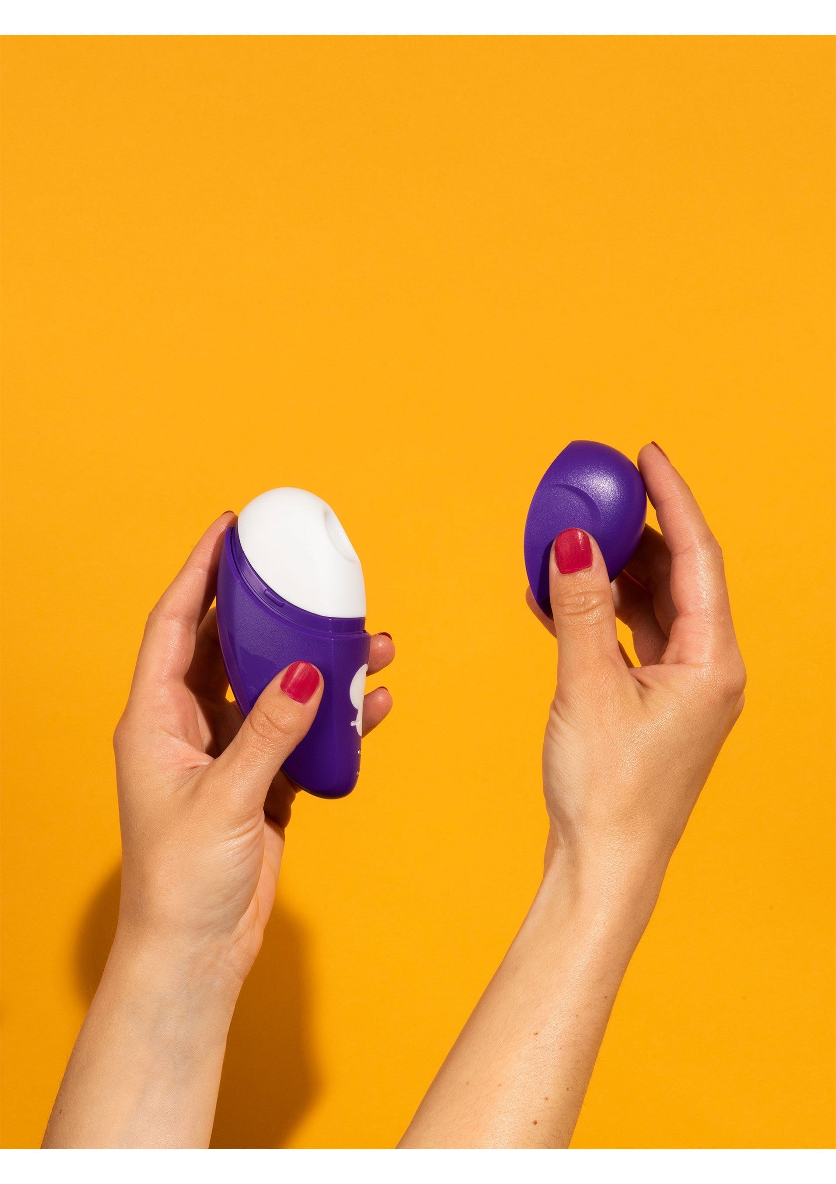 Deux mains présentant des sextoys violets sur fond jaune.; Twee handen die paarse seksspeeltjes presenteren tegen een gele achtergrond.; Two hands presenting purple sex toys against a yellow background.