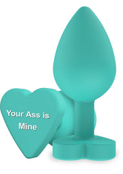 Plug anal turquoise avec motif coeur "Your Ass is Mine" pour le plaisir intime et l'exploration sexuelle.; Turquoise buttplug met hartmotief "Your Ass is Mine" voor intiem plezier en seksuele exploratie.; Teal butt plug with 'Your Ass is Mine' heart. Adult toy for intimate pleasure and sexual exploration.