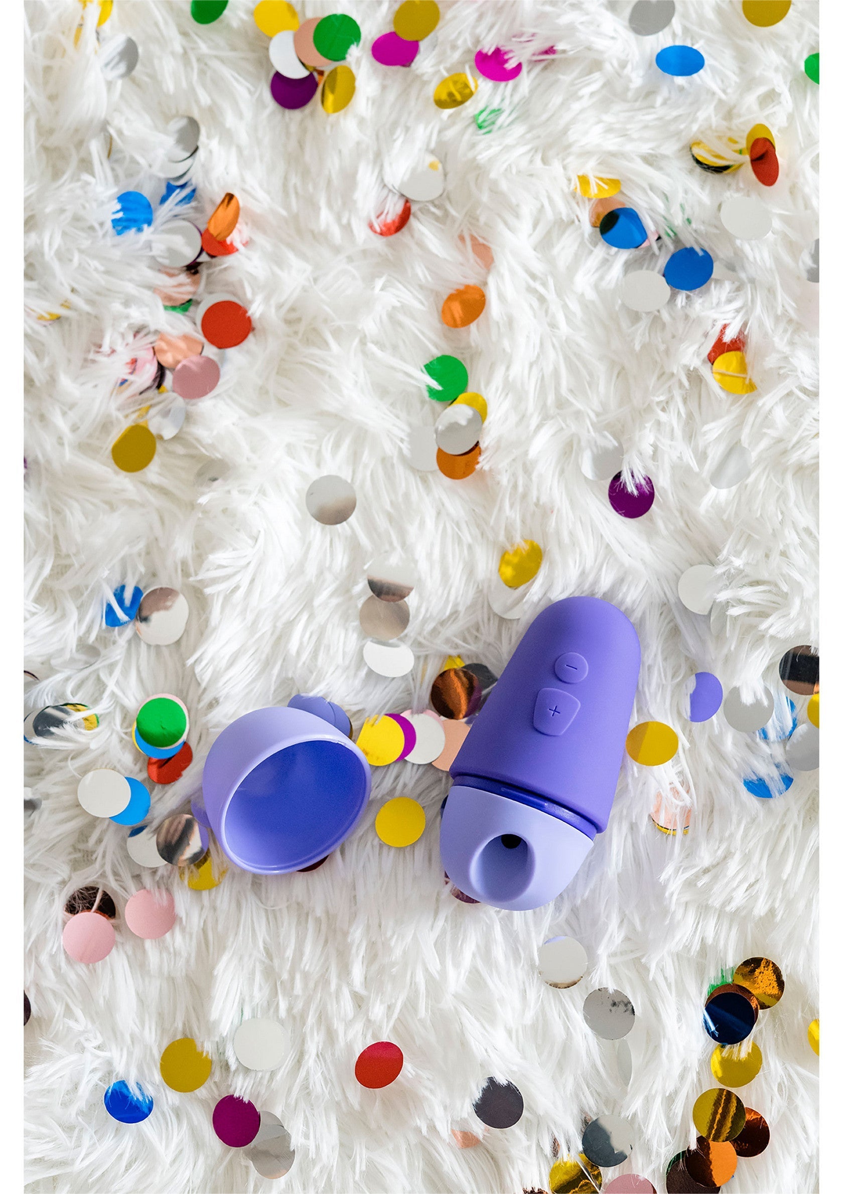 Un jouet pour homme violet sur une fourrure blanche avec des confettis colorés.; Een paars speeltje voor mannen op witte vacht met kleurrijke confetti.; A purple male pleasure toy on white fur with colorful confetti.