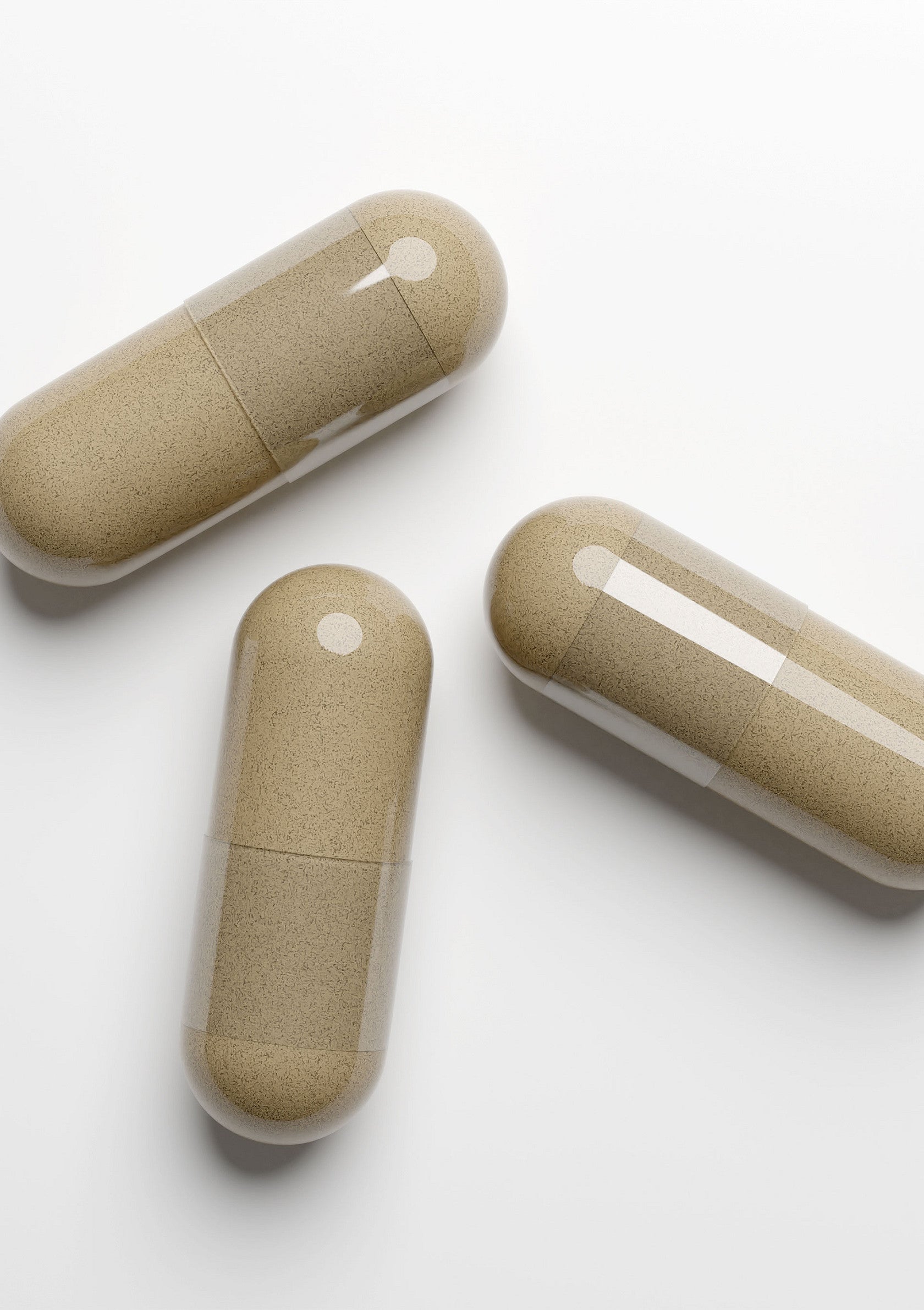 Gros plan sur trois gélules beige clair. Compléments alimentaires et vitamines.; Close-up van drie lichtbeige capsules. Voedingssupplementen en vitamines.; Close-up of three light beige capsules. Dietary supplements and vitamins.