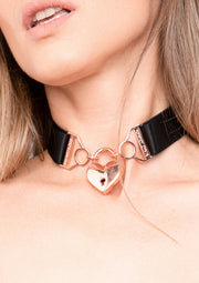 Collier ras du cou avec cadenas en forme de cœur doré, accessoire de mode féminin.; Choker met gouden hartslot, een trendy modeaccessoire voor dames.; Choker necklace with golden heart lock, a trendy fashion accessory for women.