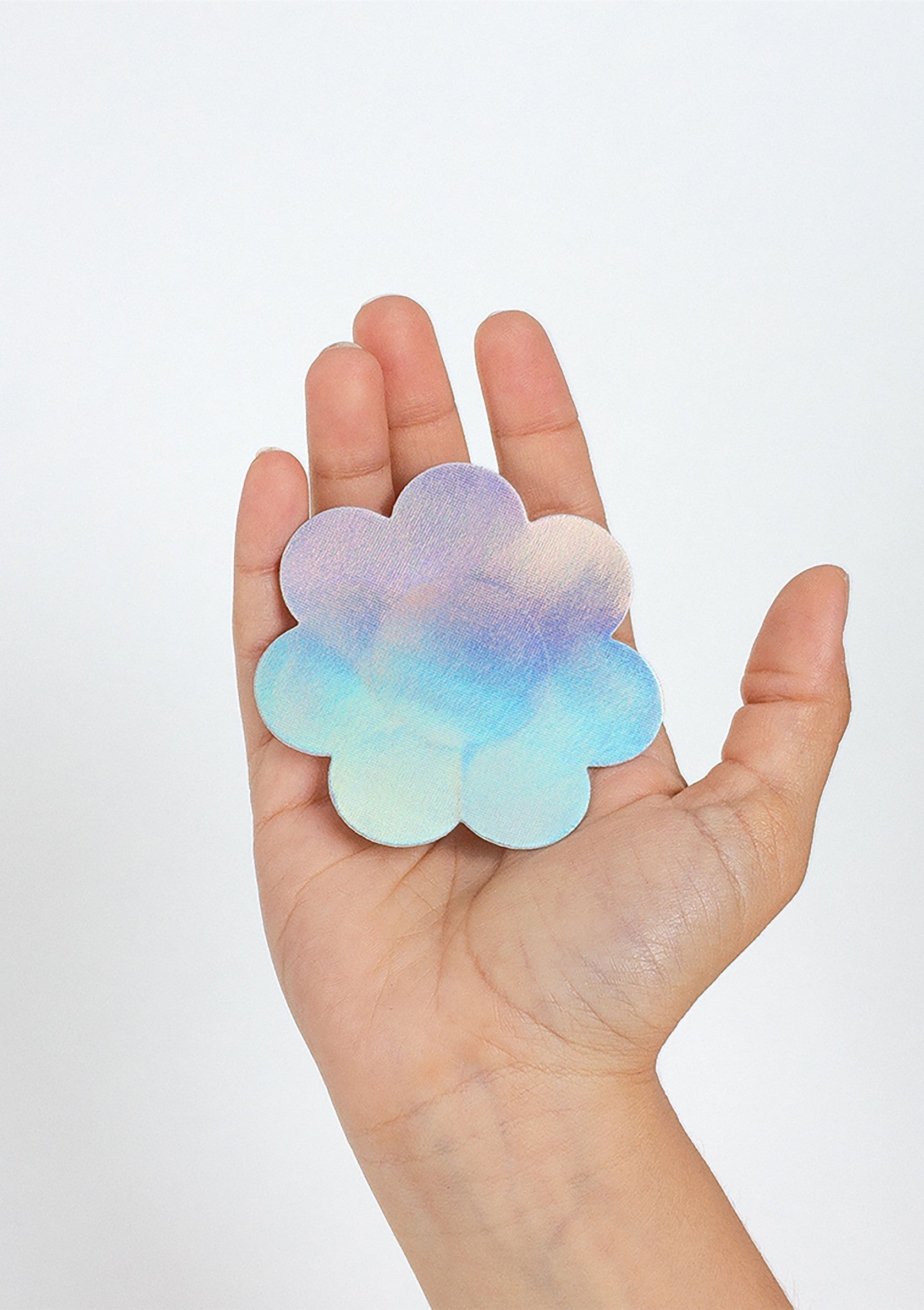 Main tenant un aimant en forme de fleur aux couleurs pastel. Décoration intérieure colorée.; Hand houdt een bloemvormige magneet vast in pastelkleuren. Kleurrijke interieurdecoratie.; Hand holding a flower-shaped magnet in pastel colors. Colorful home decor.