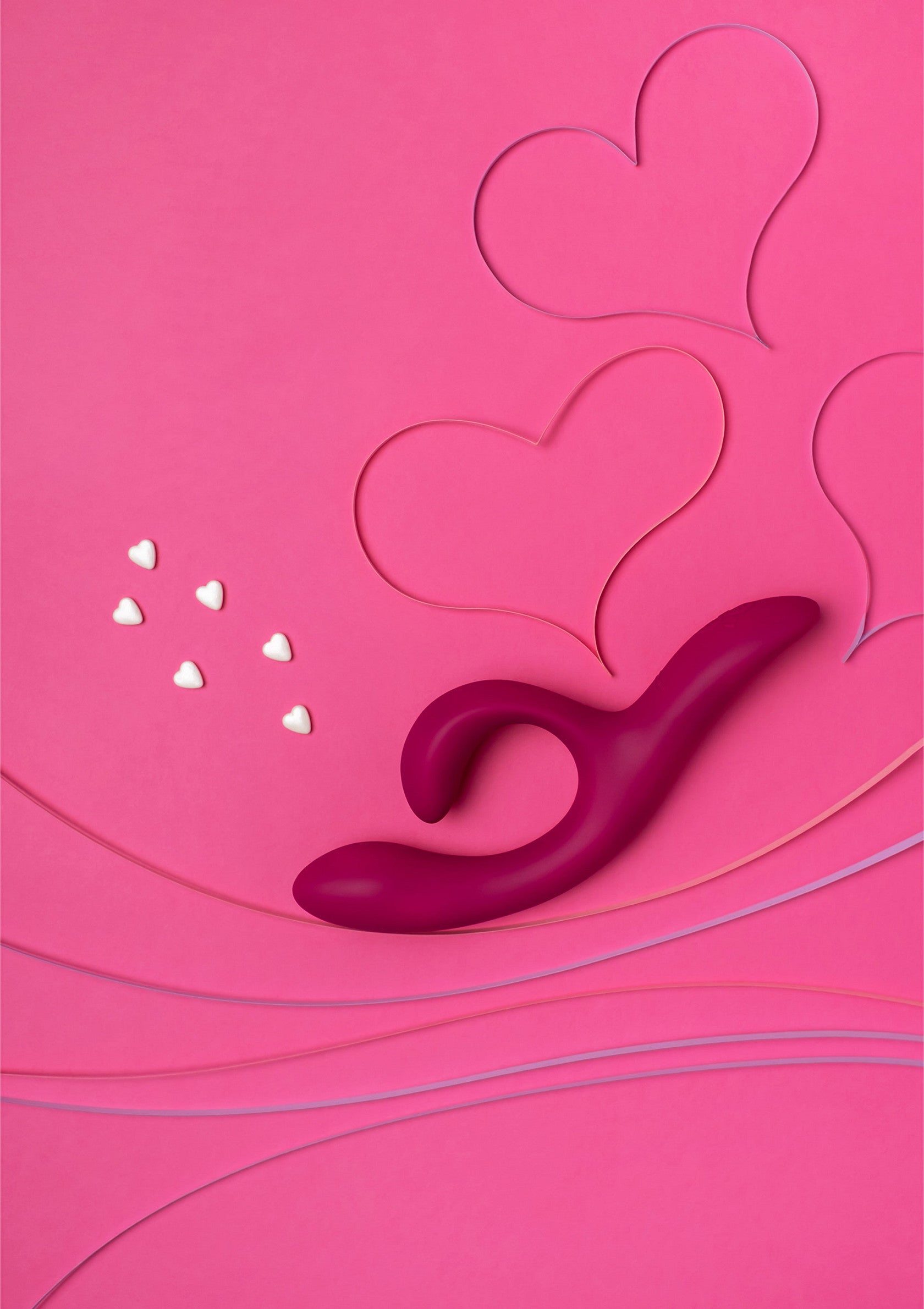 Vibromasseur rose sur fond rose avec coeurs. Plaisir et romance pour la Saint-Valentin.; Roze vibrator op roze achtergrond met hartjes. Plezier en romantiek voor Valentijnsdag.; Pink vibrator on a pink background with hearts. Pleasure and romance for Valentine's Day.