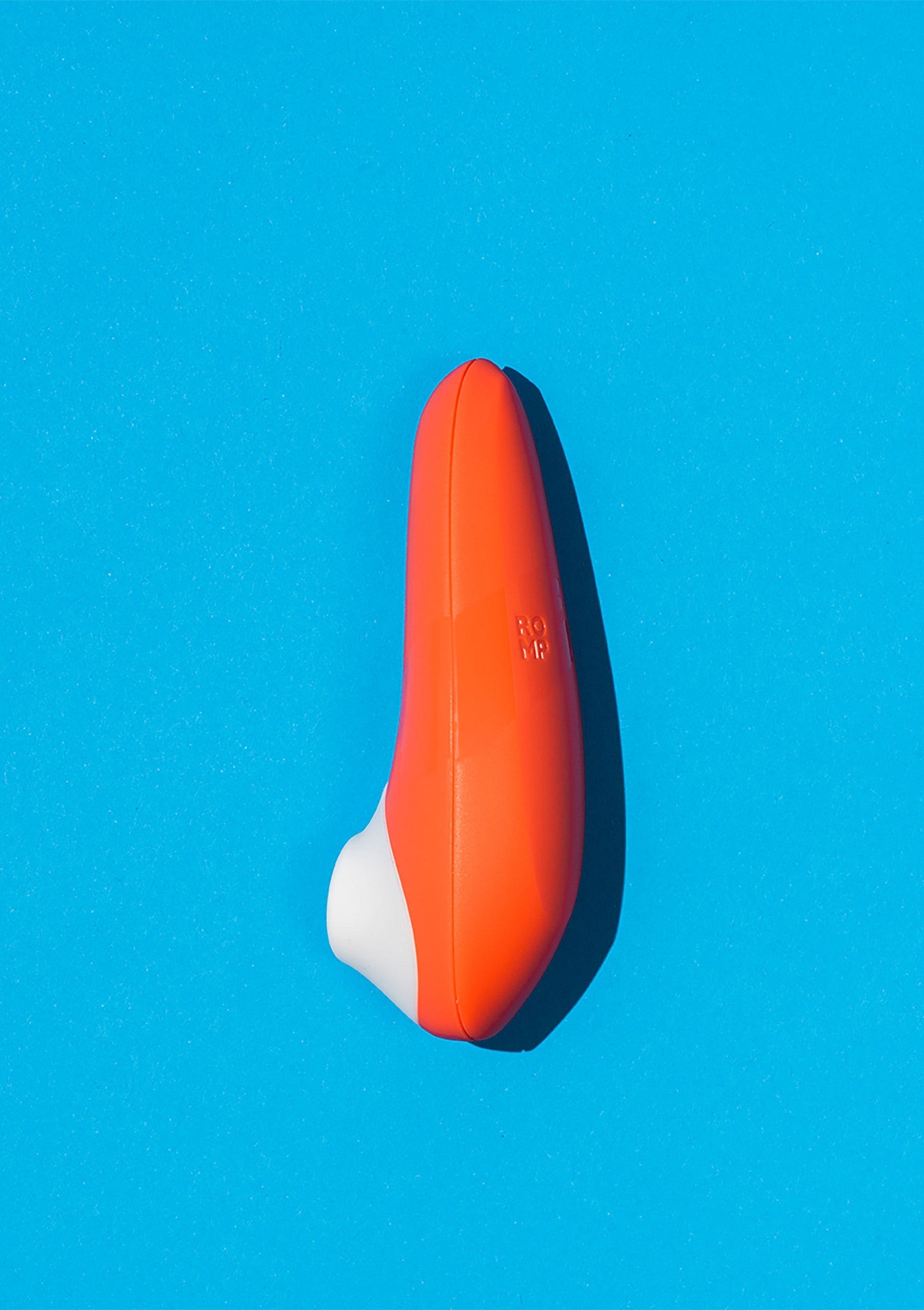 Masseur vibrant orange et blanc sur fond bleu vif pour le plaisir et la détente.; Oranje en witte vibrerende stimulator op een helderblauwe achtergrond voor plezier en ontspanning.; Orange and white vibrating massager on a bright blue background for pleasure and relaxation.