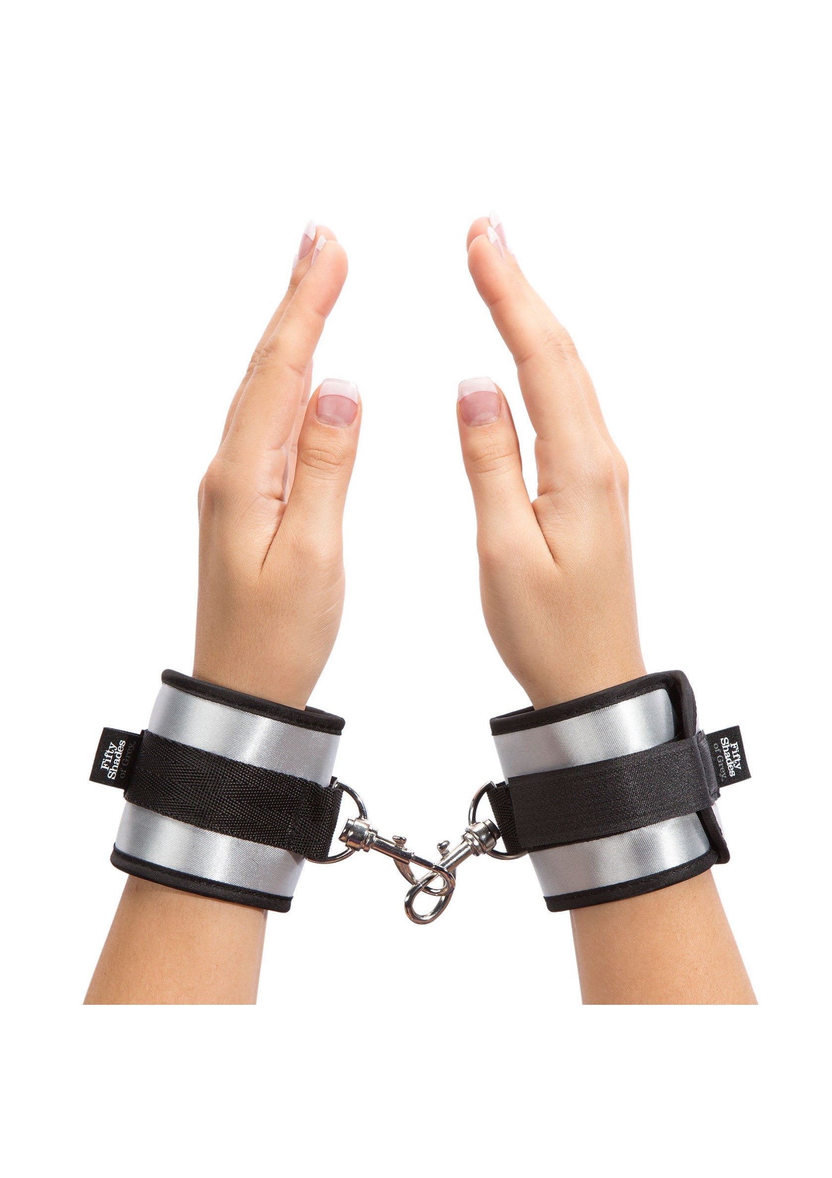 Menottes de poignet argentées avec sangles noires pour des jeux coquins.; Zilveren handboeien met zwarte bandjes voor ondeugende spelletjes.; Silver wrist cuffs with black straps for kinky fun.