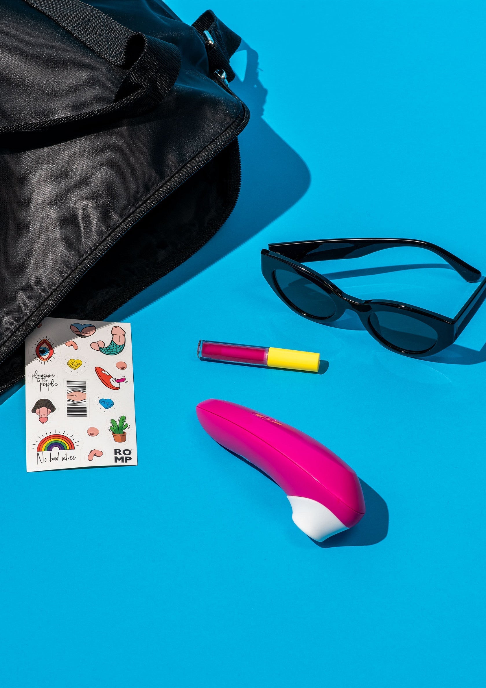 Sac noir, lunettes de soleil, autocollants et vibromasseur rose sur fond bleu. Idéal pour une escapade coquine!; Zwarte tas, zonnebril, stickers en roze vibrator op blauwe achtergrond. Ideaal voor een ondeugend uitje!; Black bag, sunglasses, stickers, & pink vibrator on blue. Great for a naughty getaway!  