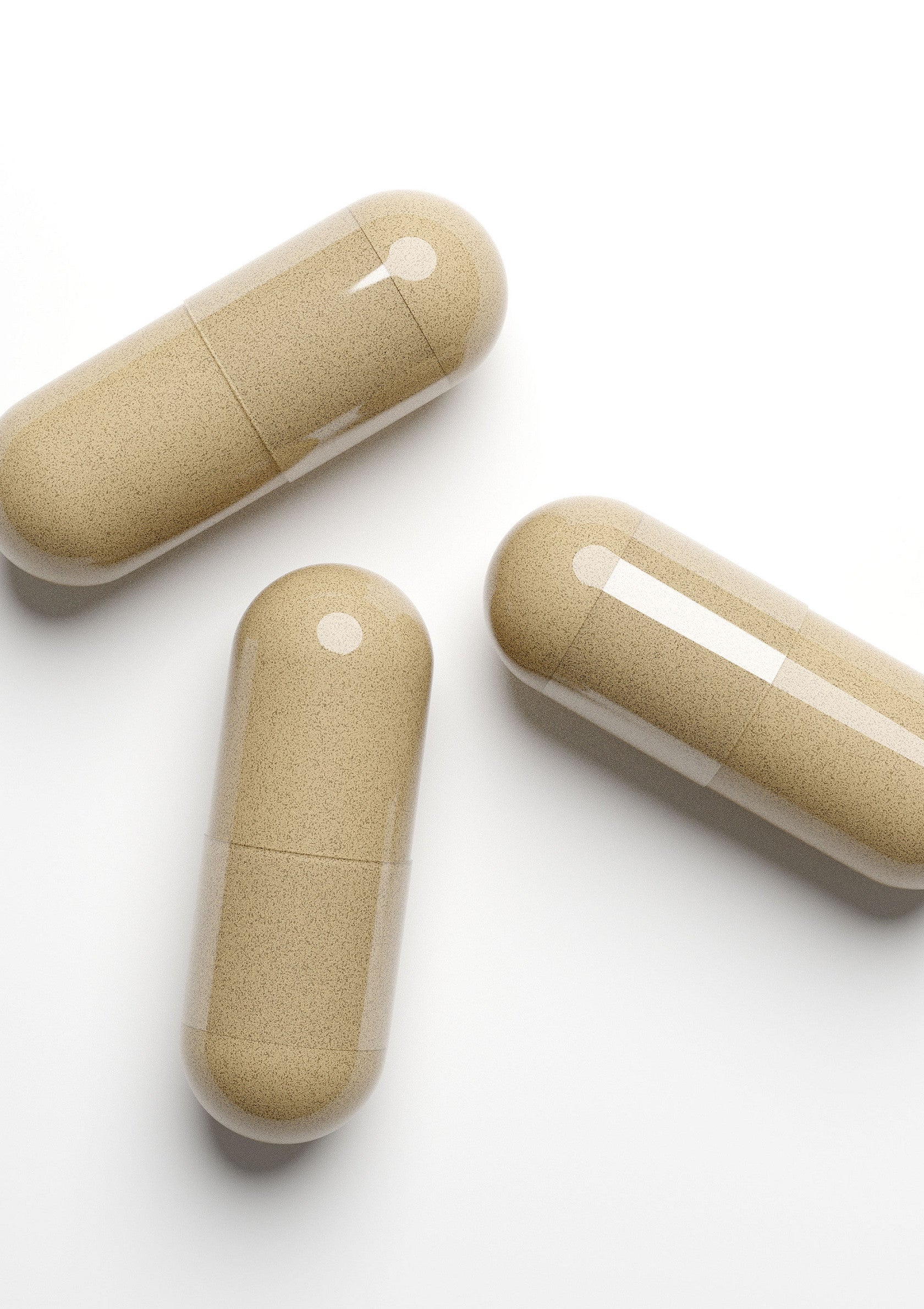 Gros plan de trois gélules beiges sur fond blanc. Compléments alimentaires et vitamines.; Close-up van drie beige capsules op een witte achtergrond. Voedingssupplementen en vitaminen.; Close-up of three beige capsules on a white background. Food supplements and vitamins.