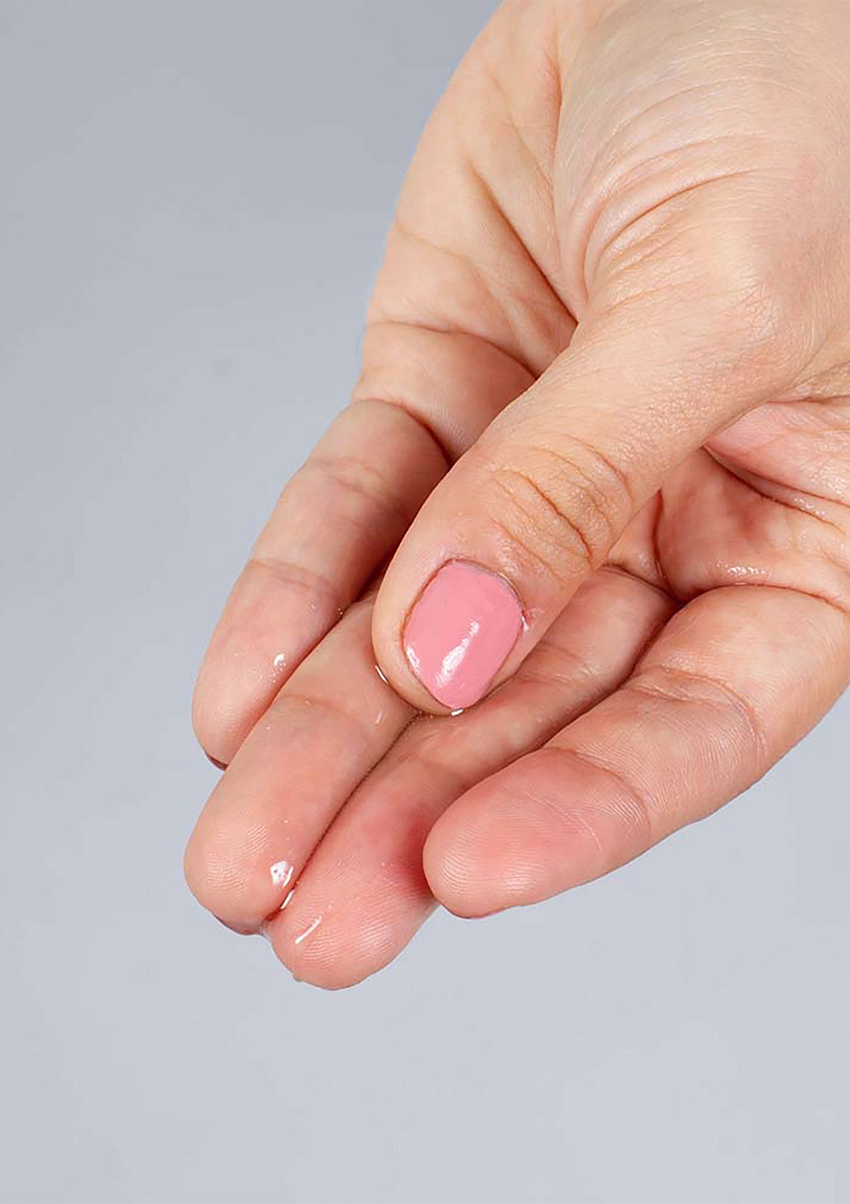 Main féminine avec une goutte de sérum transparent. Hydratation intense pour une peau douce et éclatante. ; Vrouwenhand met druppel helder serum. Intense hydratatie voor een zachte, stralende huid.; Woman's hand with drop of clear serum. Intense hydration for soft, glowing skin.