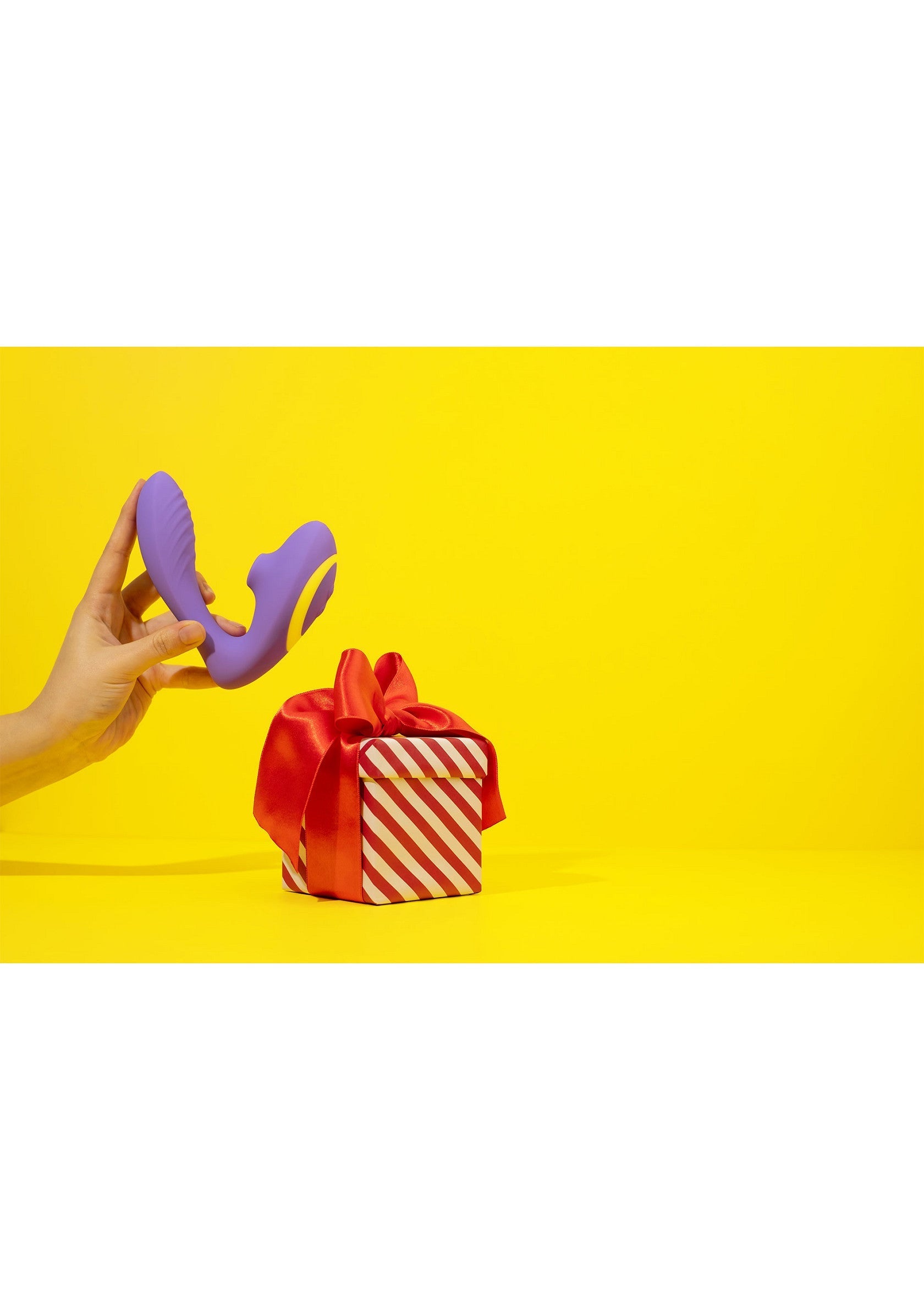 Cadeau coquin. Vibromasseur violet présenté avec un cadeau sur fond jaune. Plaisir et sensualité.; Vunzig cadeau. Paarse vibrator gepresenteerd met een cadeau op een gele achtergrond. Plezier en sensualiteit.; Naughty gift. Purple vibrator presented with a gift on a yellow background. Pleasure and sensuality.