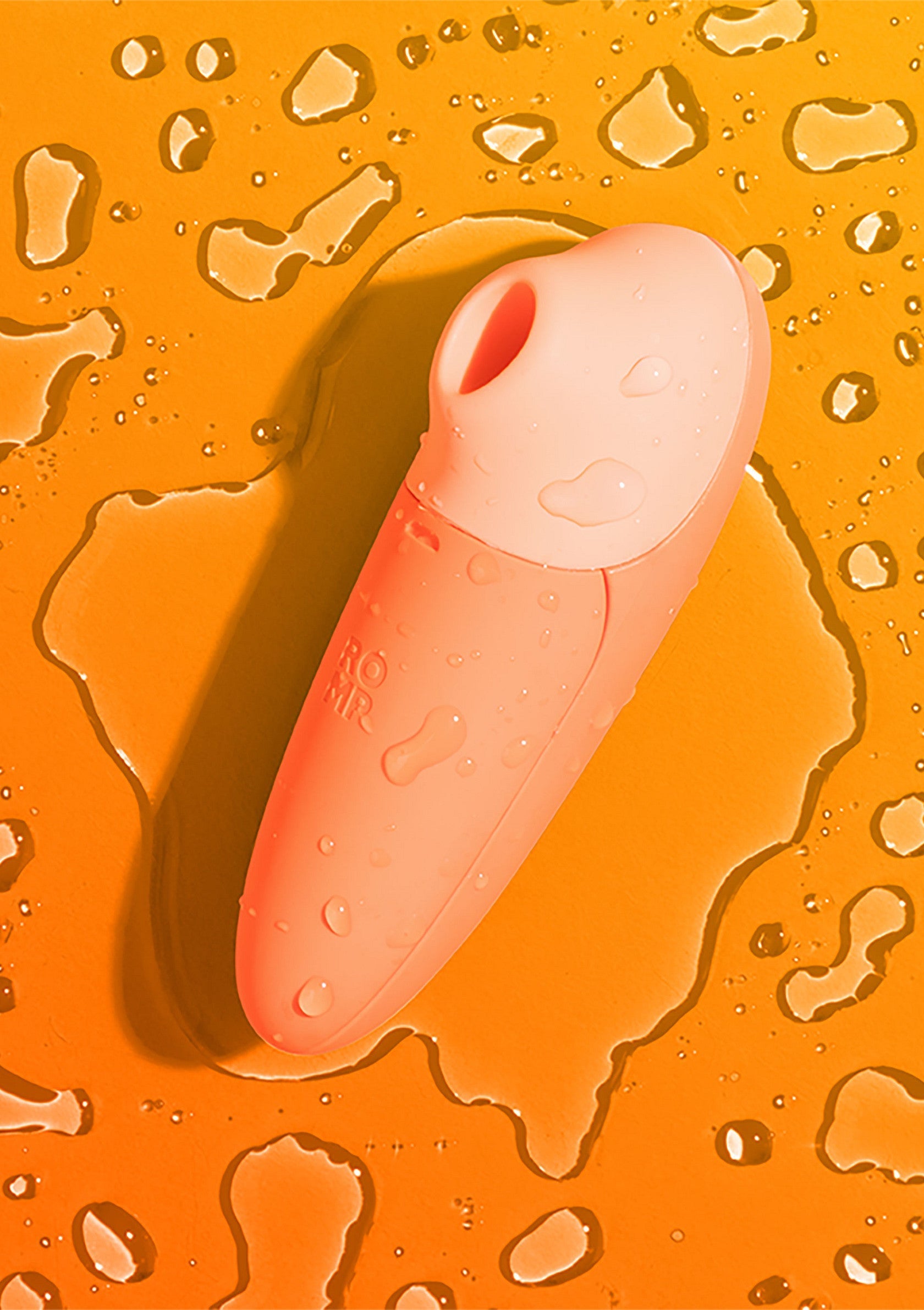Sextoy rose sur fond orange avec des gouttes d'eau. Plaisir et sensualité garantis.; Roze seksspeeltje op oranje achtergrond met waterdruppels. Plezier en sensualiteit gegarandeerd.; Pink sex toy on an orange background with water droplets. Pleasure and sensuality guaranteed.