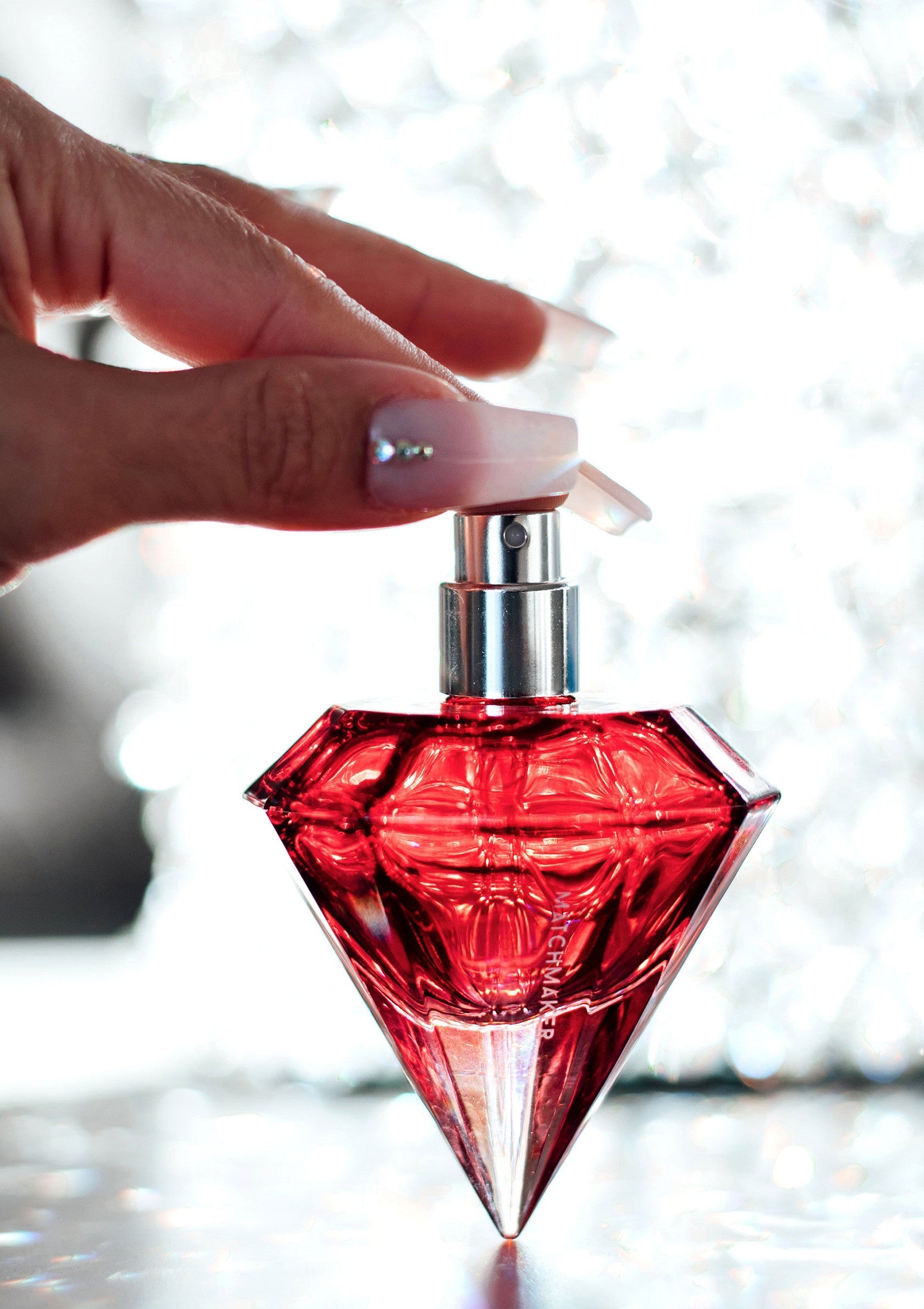 Flacon de parfum rouge en forme de diamant, luxueux et élégant.; Rode parfumfles in de vorm van een diamant, luxe en elegant.; Red diamond-shaped perfume bottle, luxurious and elegant.